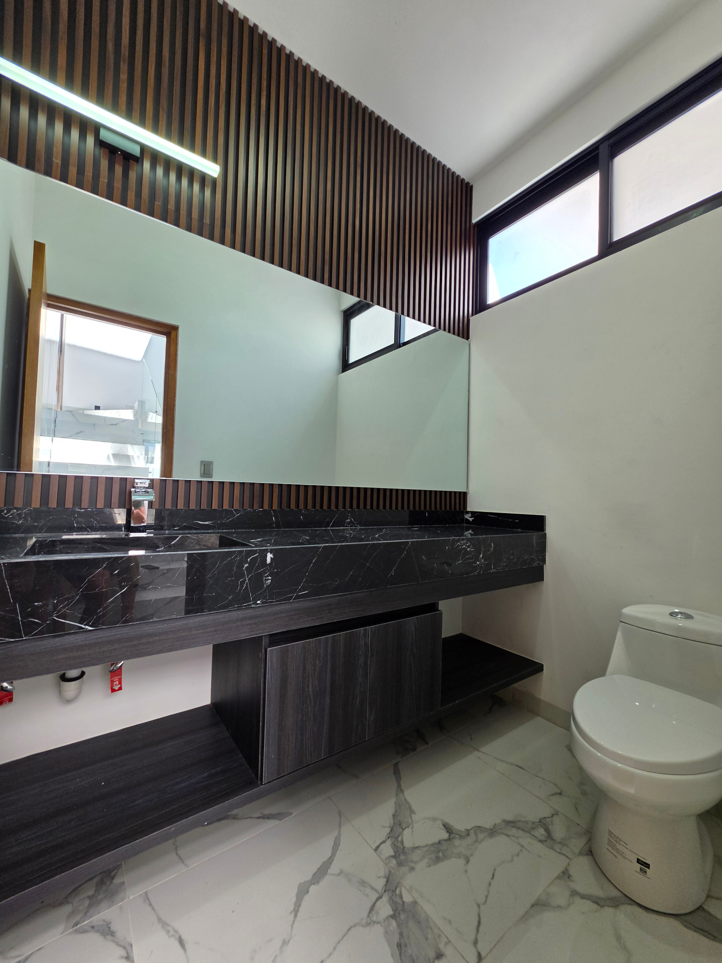 Baño con cubierta de mármol negro y detalles en madera