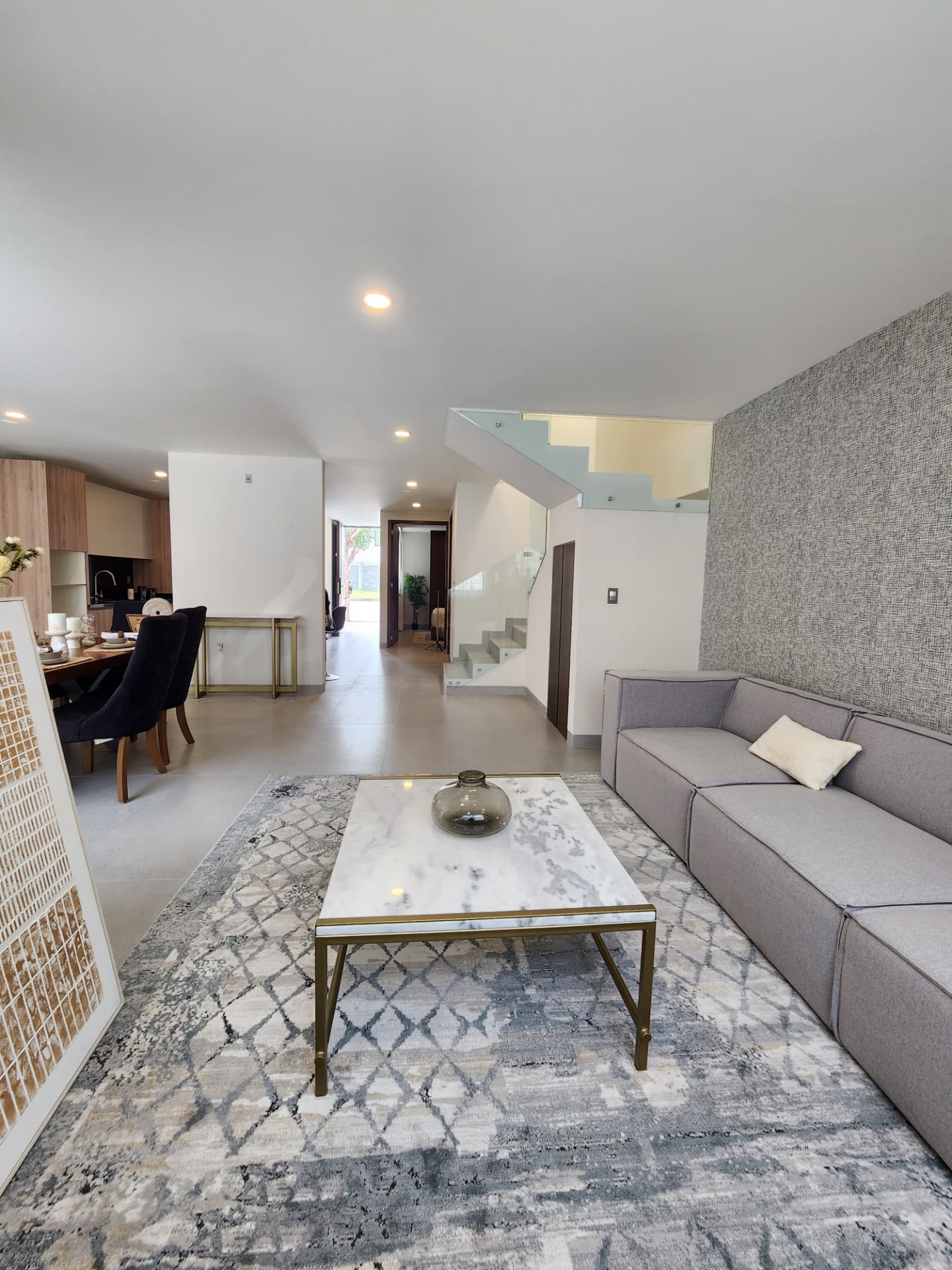 Sala amplia con escalera de cristal y estancia integrada