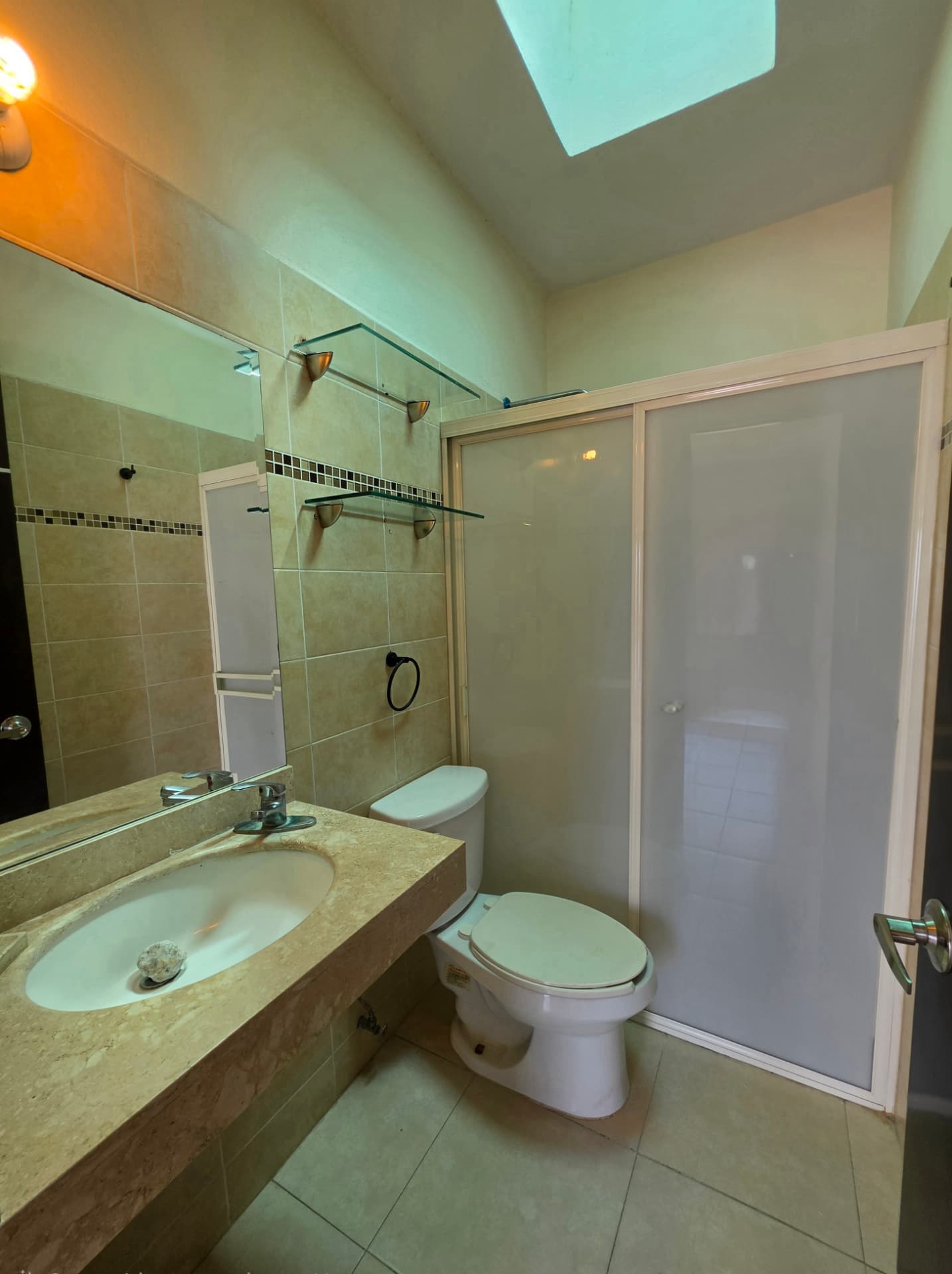 Baño completo con regadera, cubierta de mármol y tragaluz