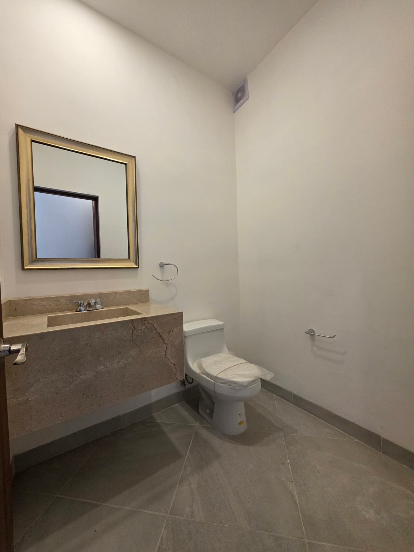 Medio baño con lavabo en cubierta de mármol y espejo enmarcado