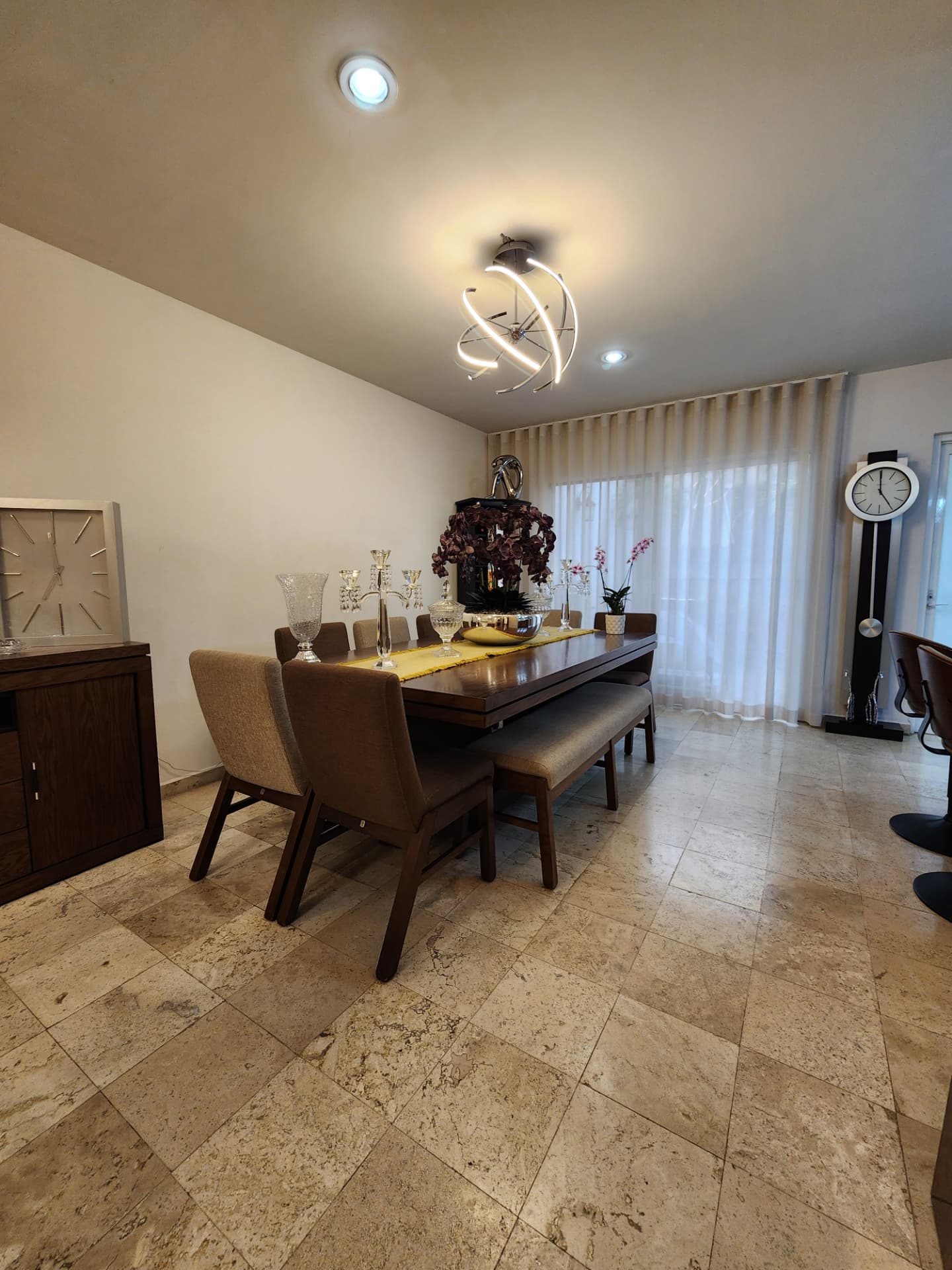 Comedor amplio con candil LED y ventanal hacia el patio