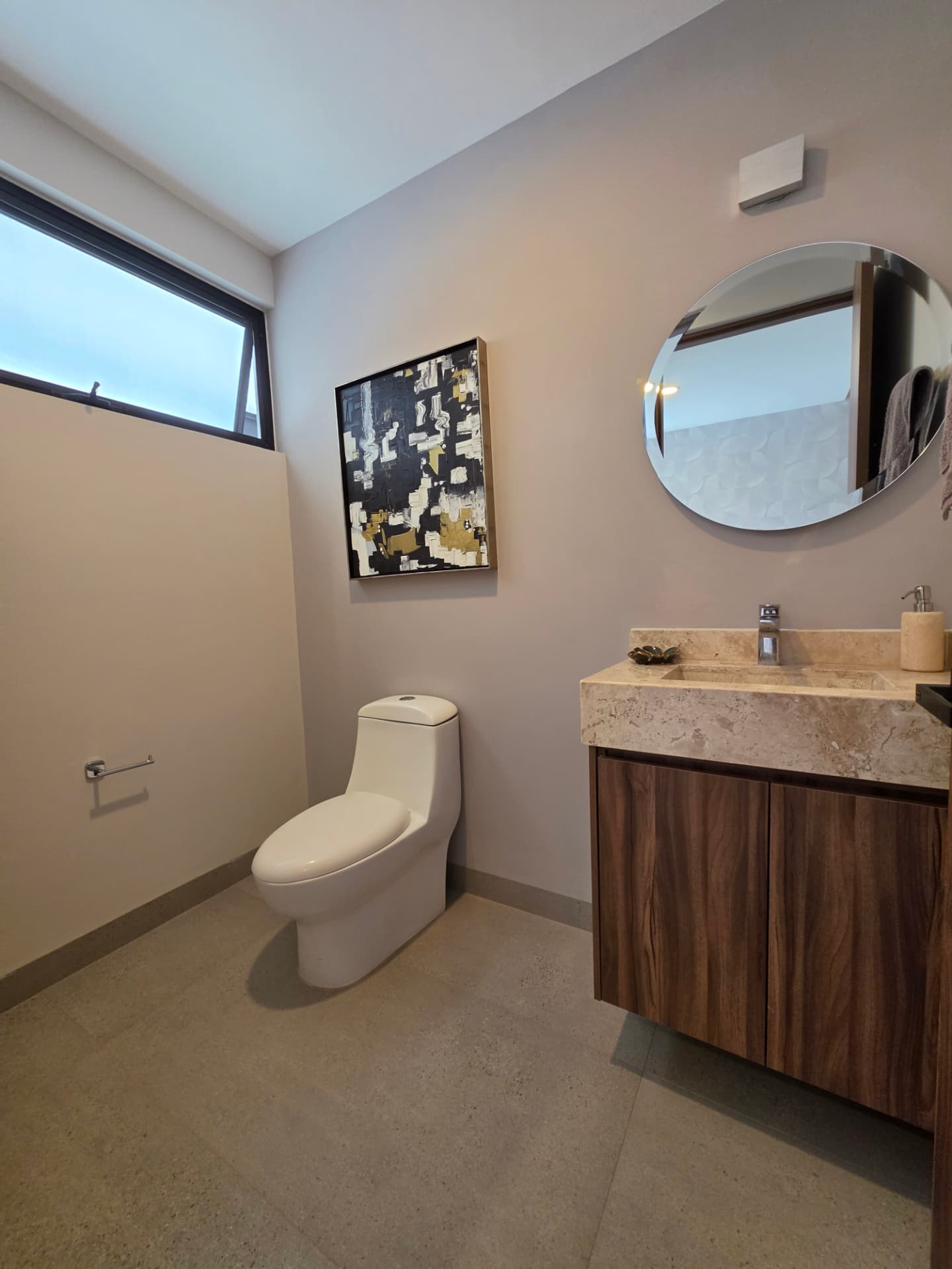 Medio baño con cubierta de mármol y espejo circular