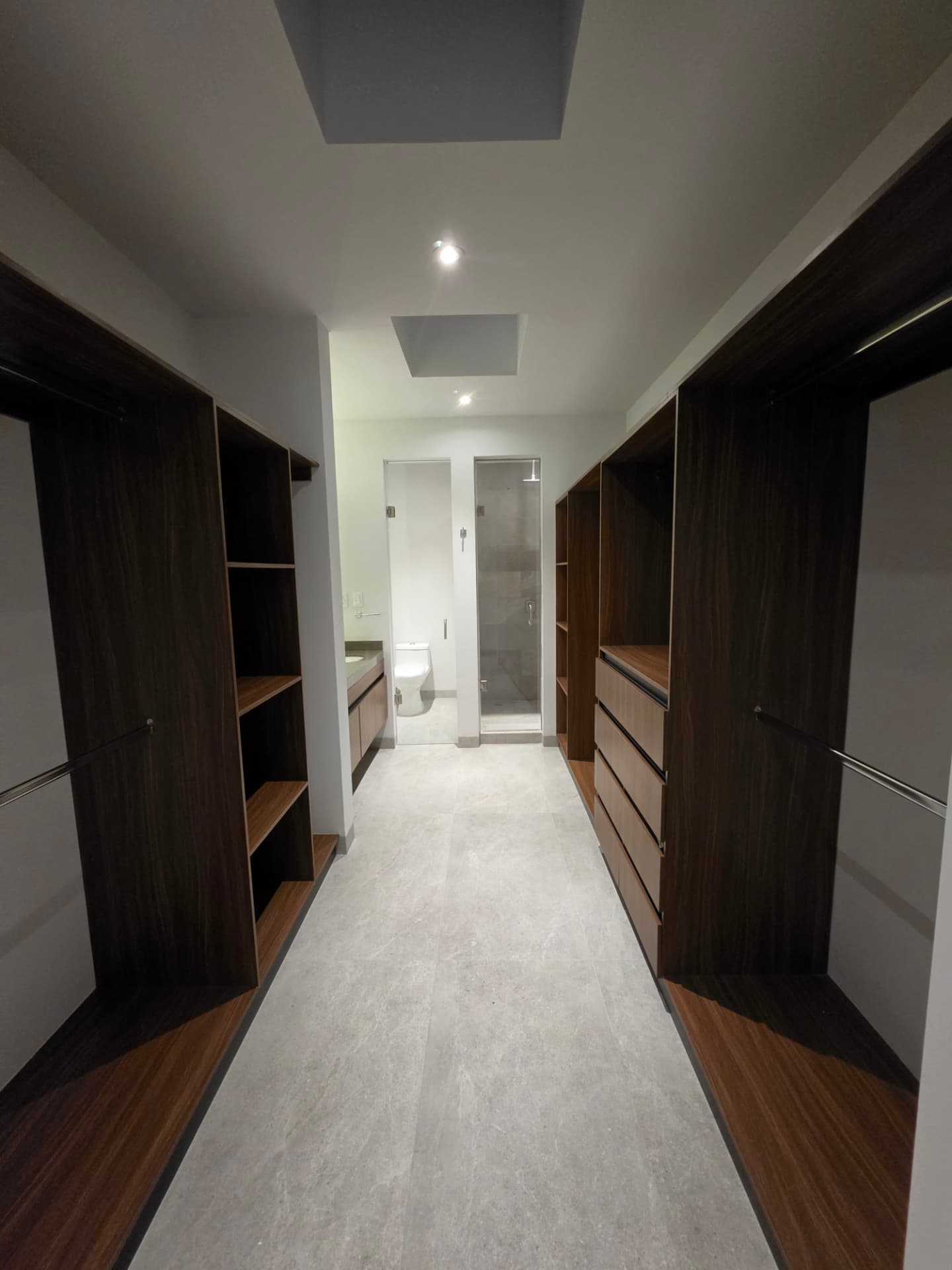 Vestidor doble con carpintería en nogal, tragaluces y acceso directo al baño principal