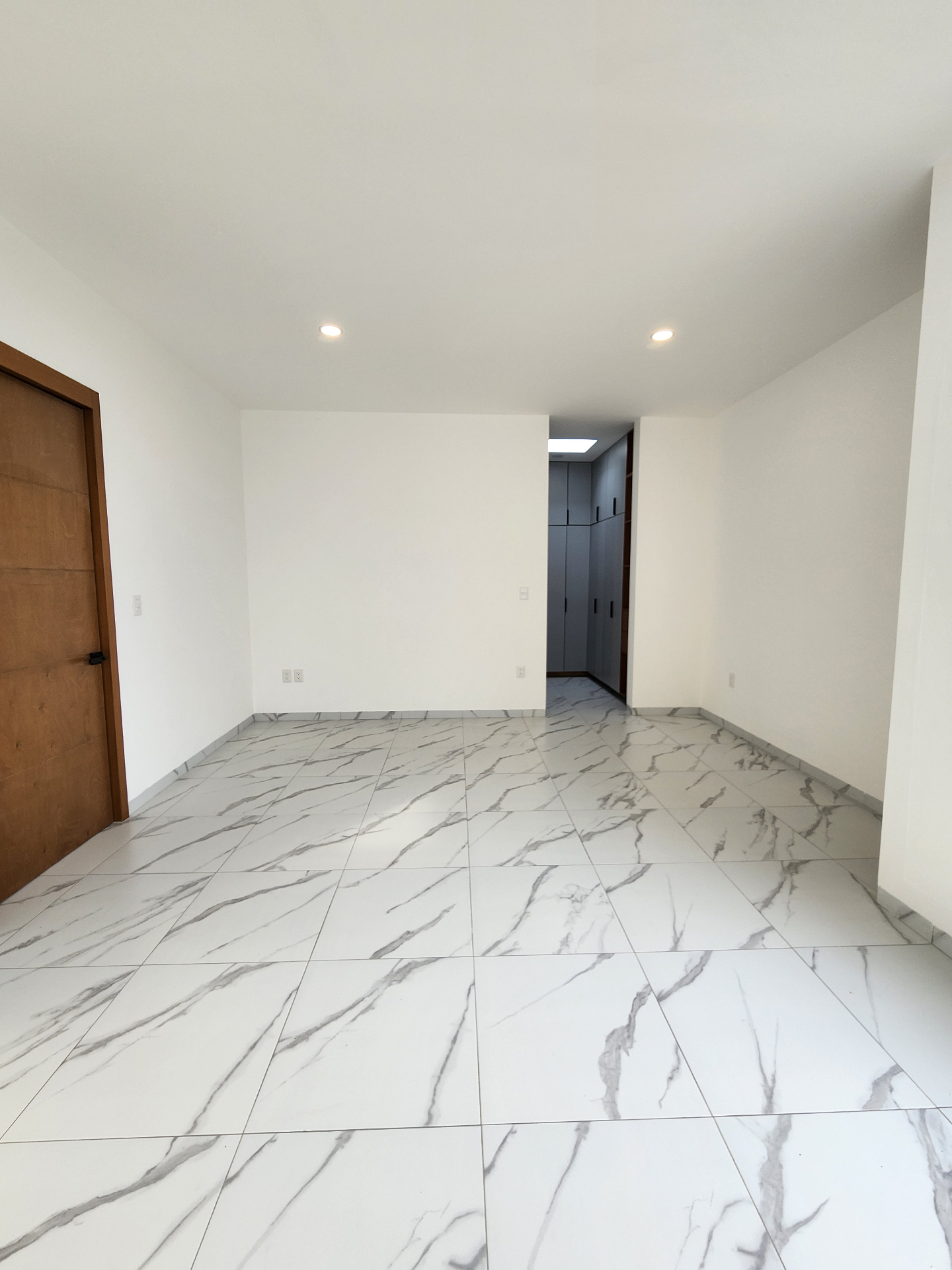 Habitación amplia con acabados neutros y acceso a vestidor
