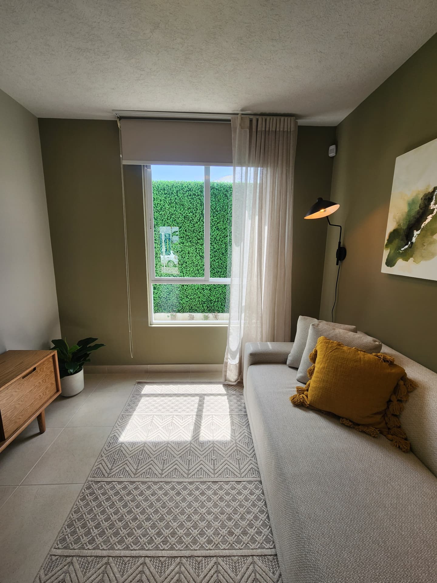 Estancia con ventanal, cortinas y muro de acento verde