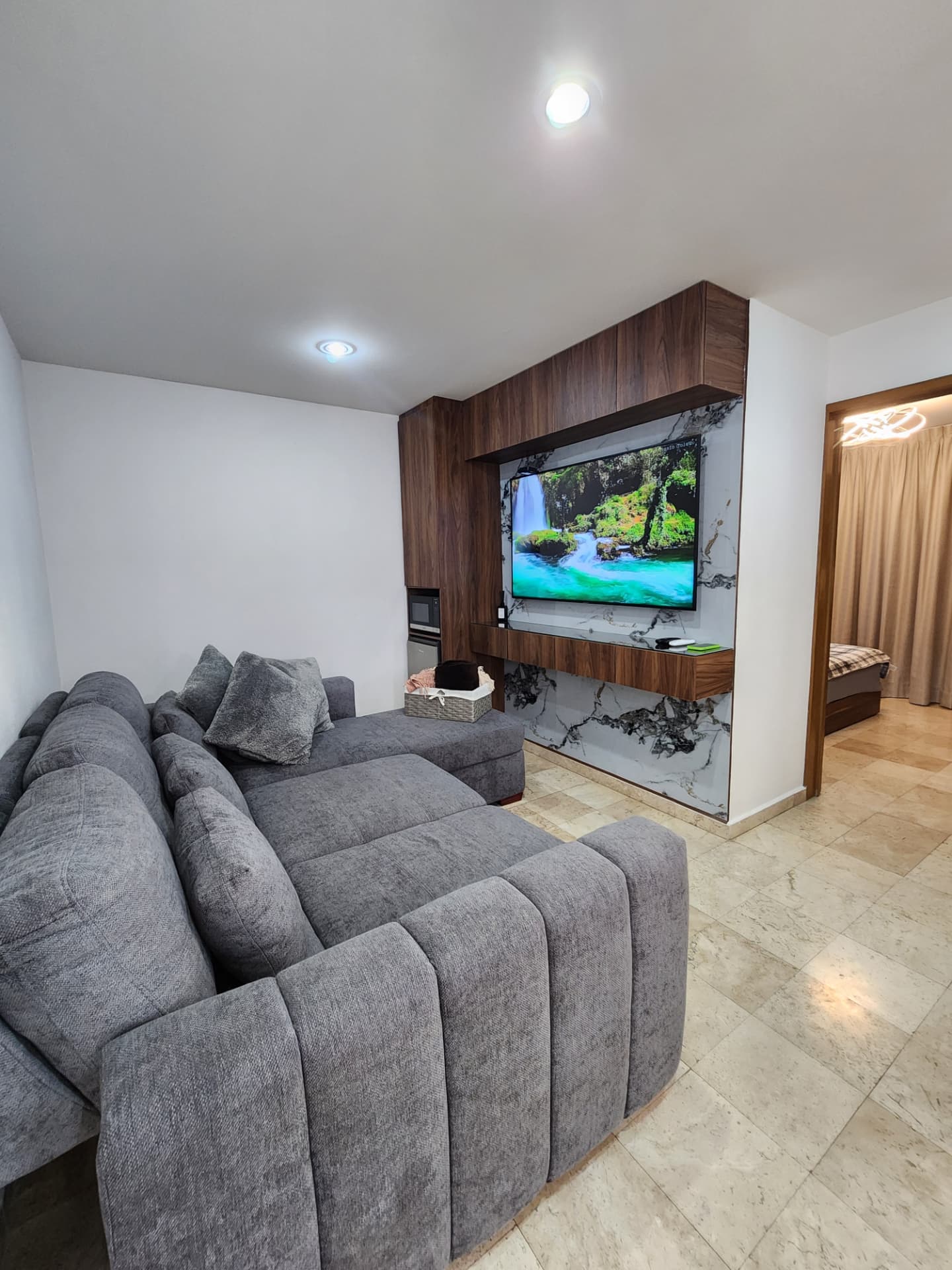 Sala de TV en planta alta con muro de madera y mármol