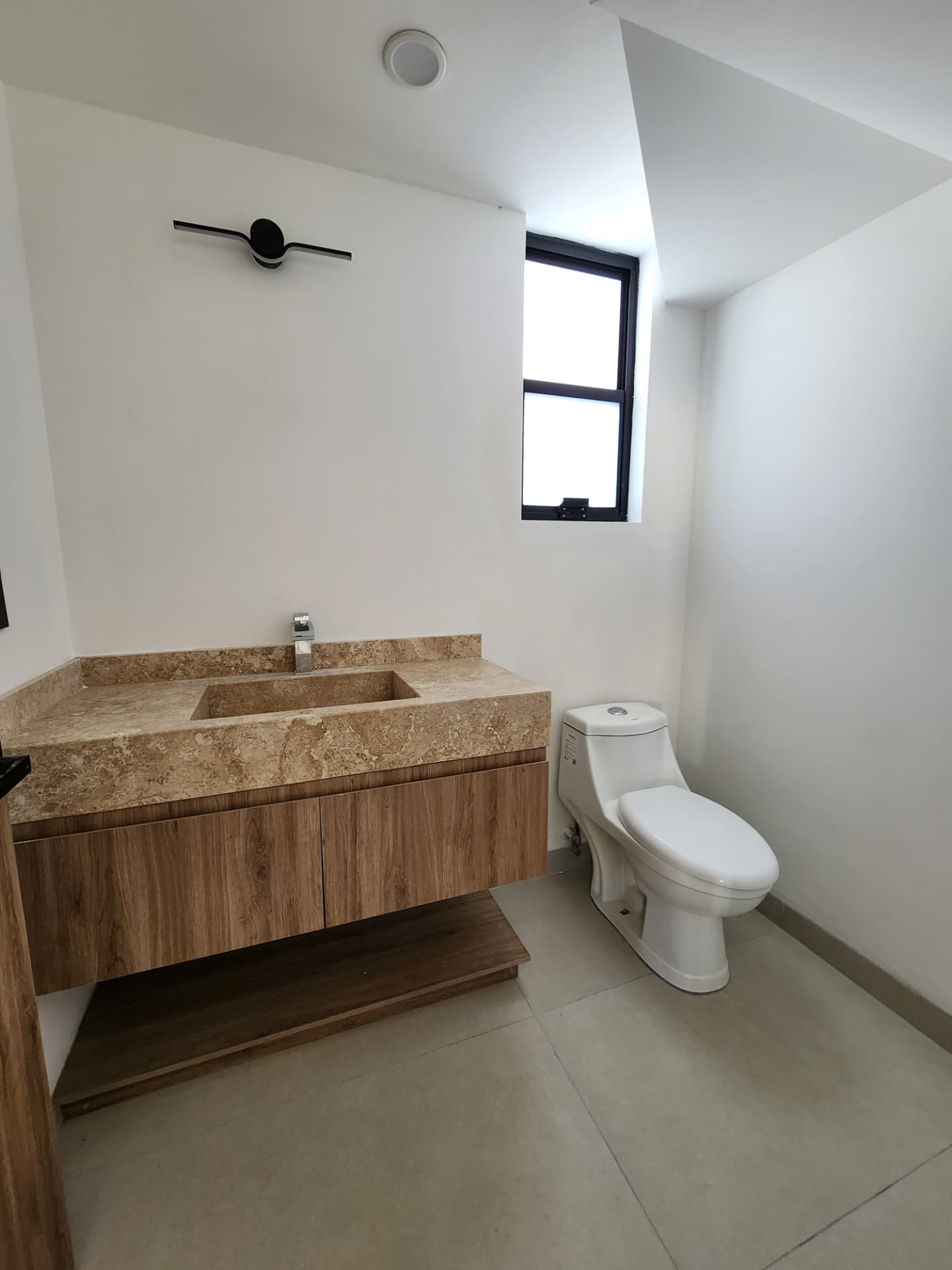 Medio baño con cubierta de mármol travertino y mueble de madera