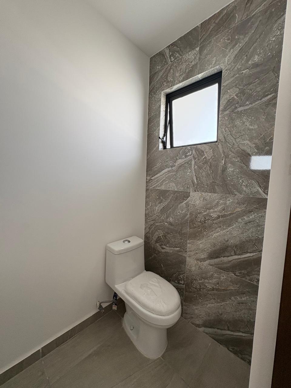 Baño con muro de mármol y ventana