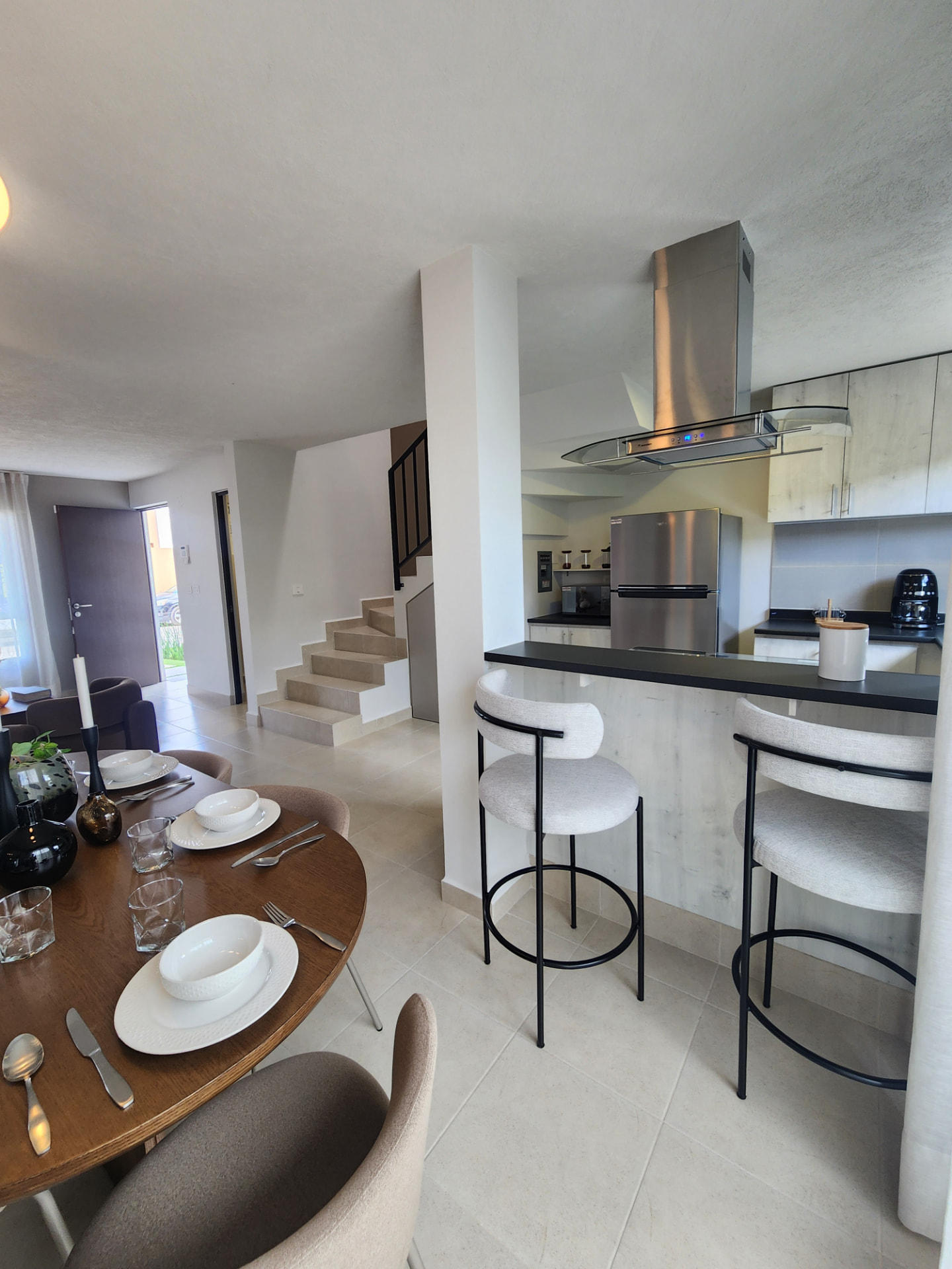 Comedor y barra de cocina con vista a la escalera y acceso principal