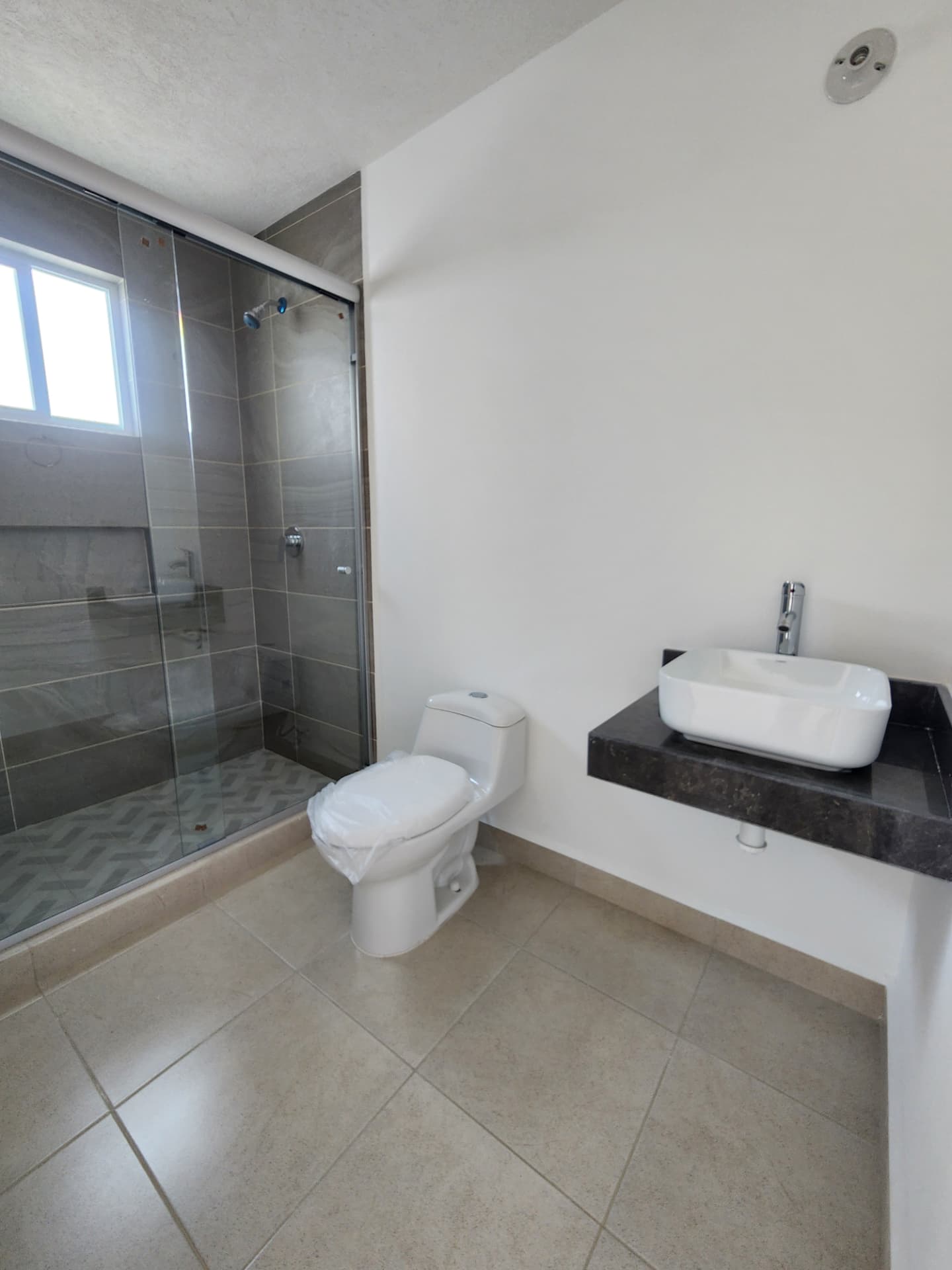 Baño completo con regadera de cristal templado y cubierta de mármol