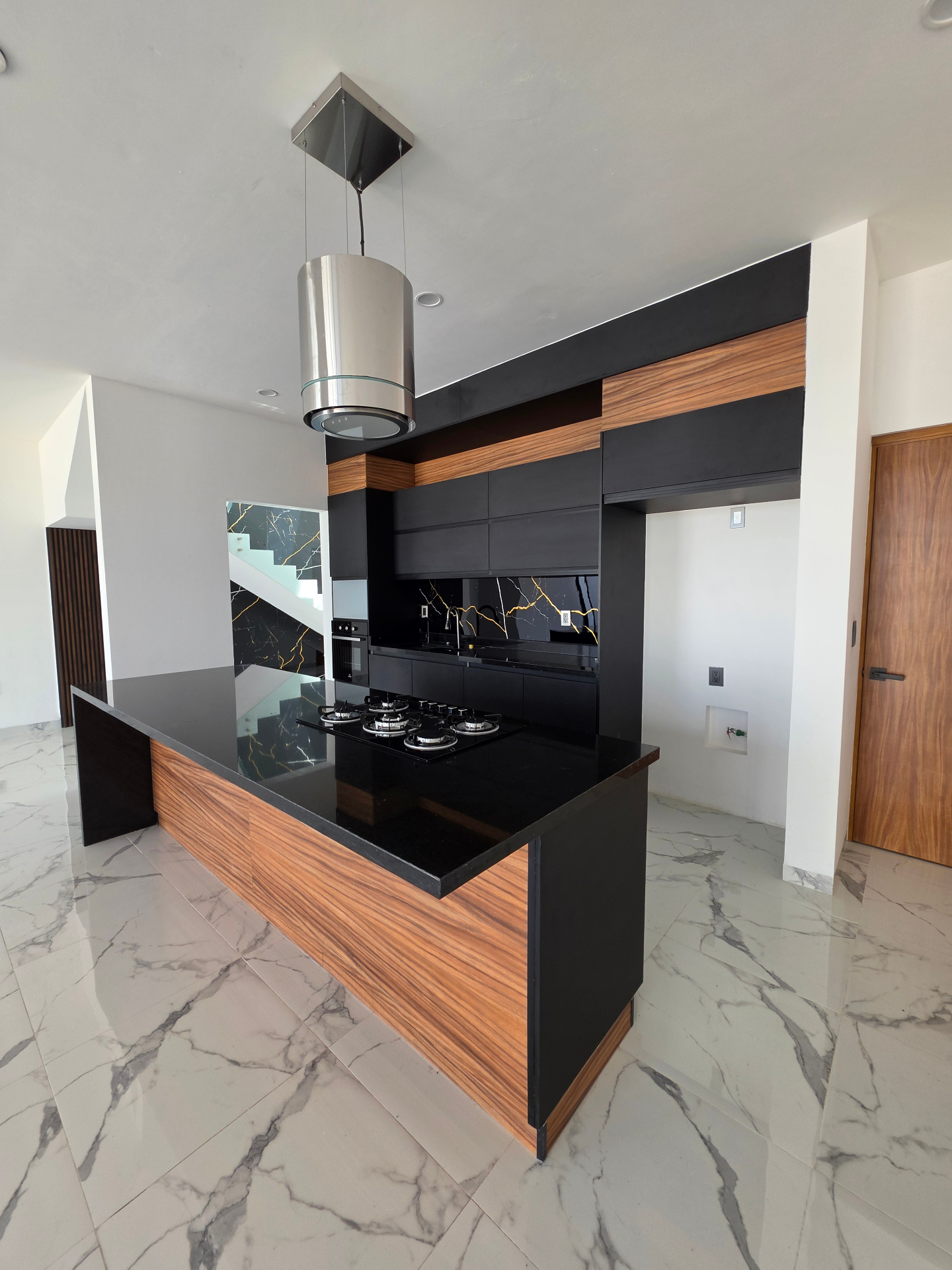 Cocina equipada con acabados en madera y mármol negro