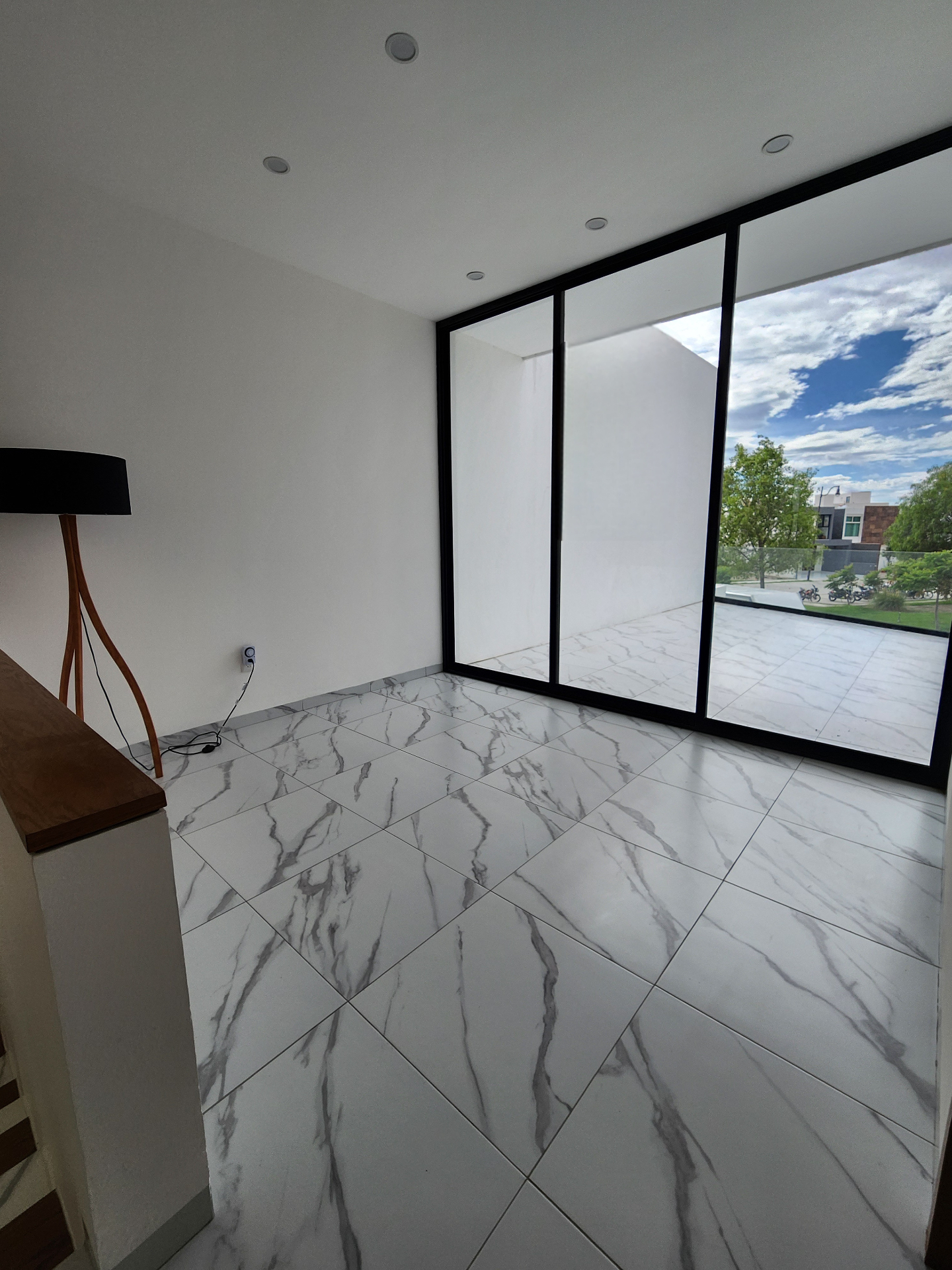 Terraza conectada a estancia interior con ventanales corredizos de piso a techo