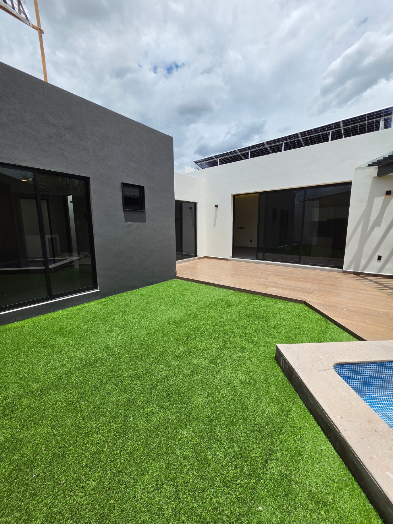 Jardín con pasto sintético, deck y vista a paneles solares