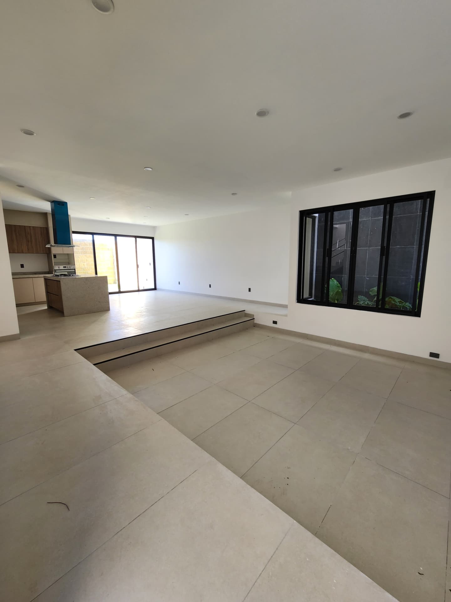 Sala y comedor a doble nivel con ventanales corredizos y vista al jardín interior