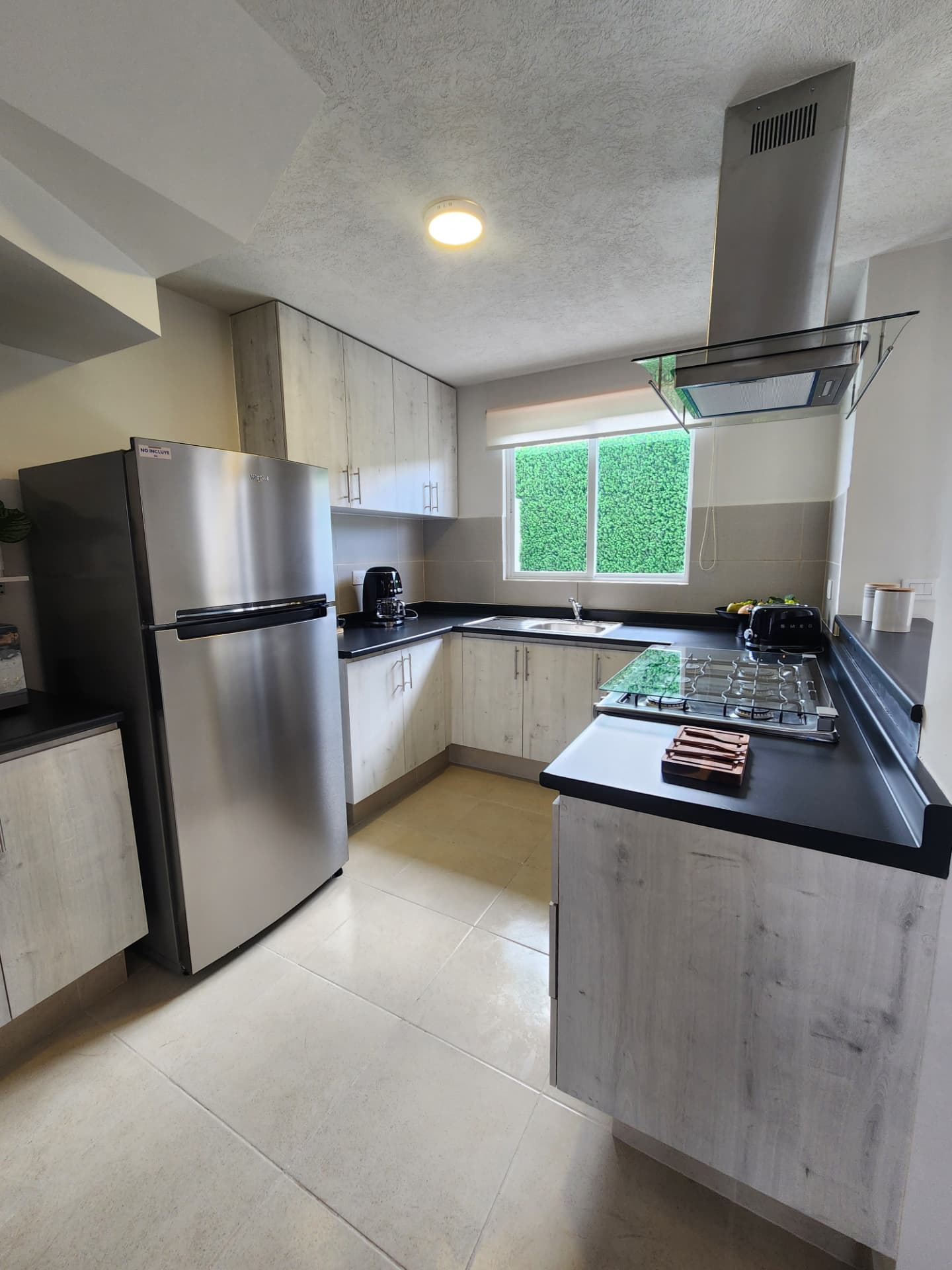Cocina equipada en U con campana de cristal, parrilla y alacenas