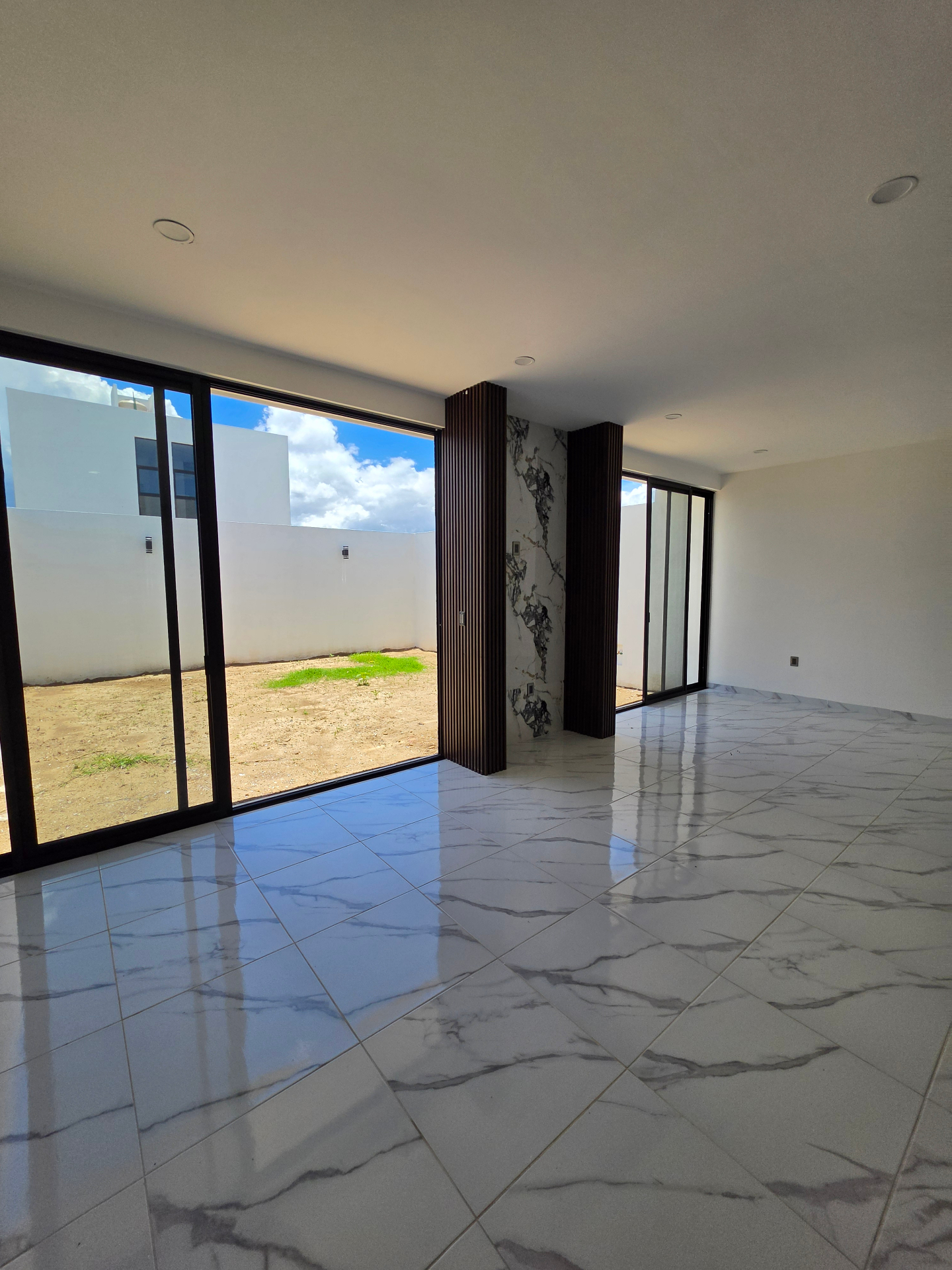 Estancia amplia con ventanales corredizos, piso porcelánico y detalles en mármol y listones