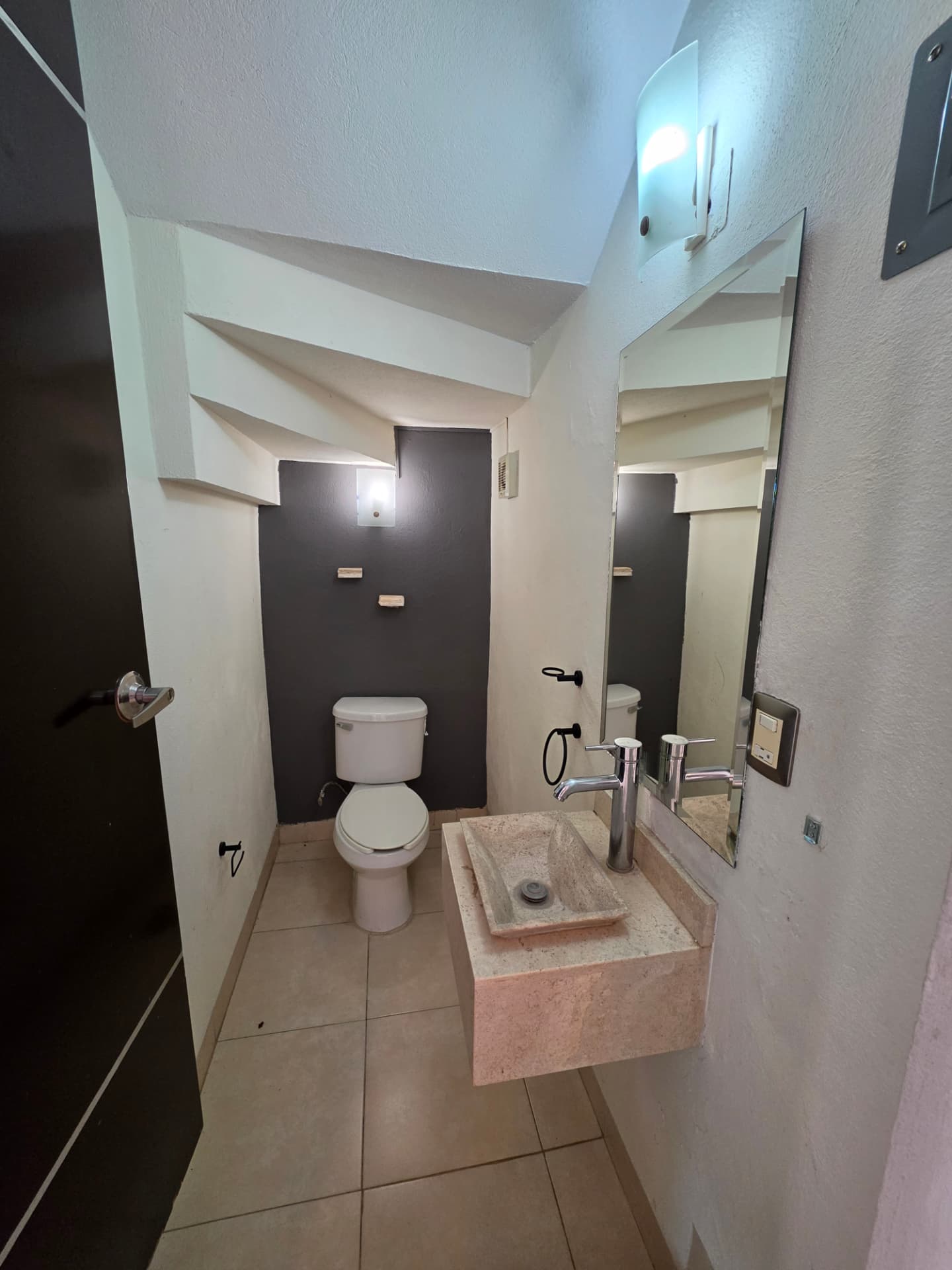 Medio baño con lavamanos de cantera y espejo
