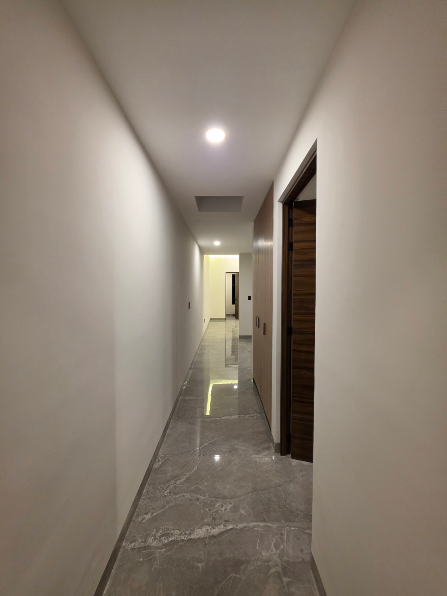 Pasillo interior con puertas de madera y piso de mármol