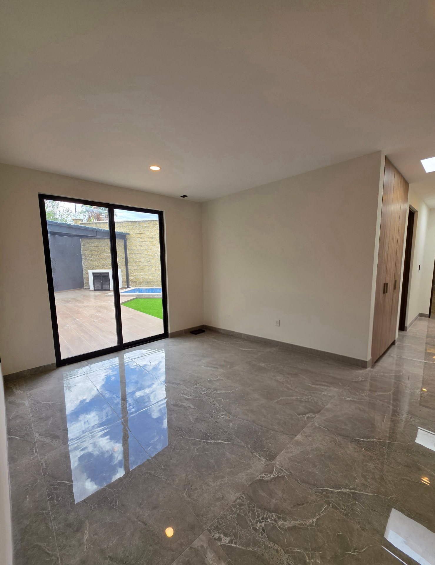 Recámara con ventanal corredizo hacia terraza y alberca, closet de madera integrado