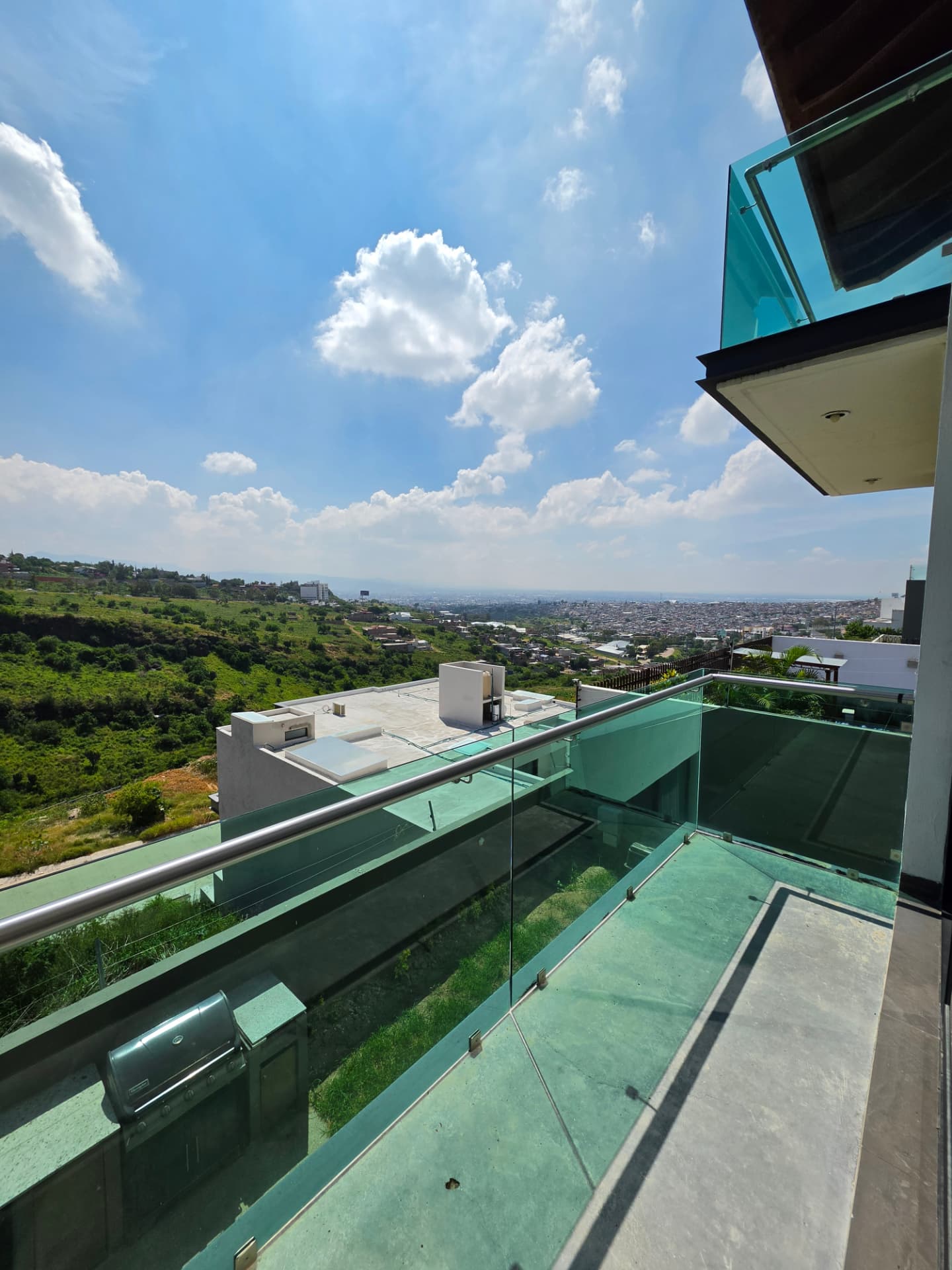 Balcón con barandal de cristal y vista a la ciudad