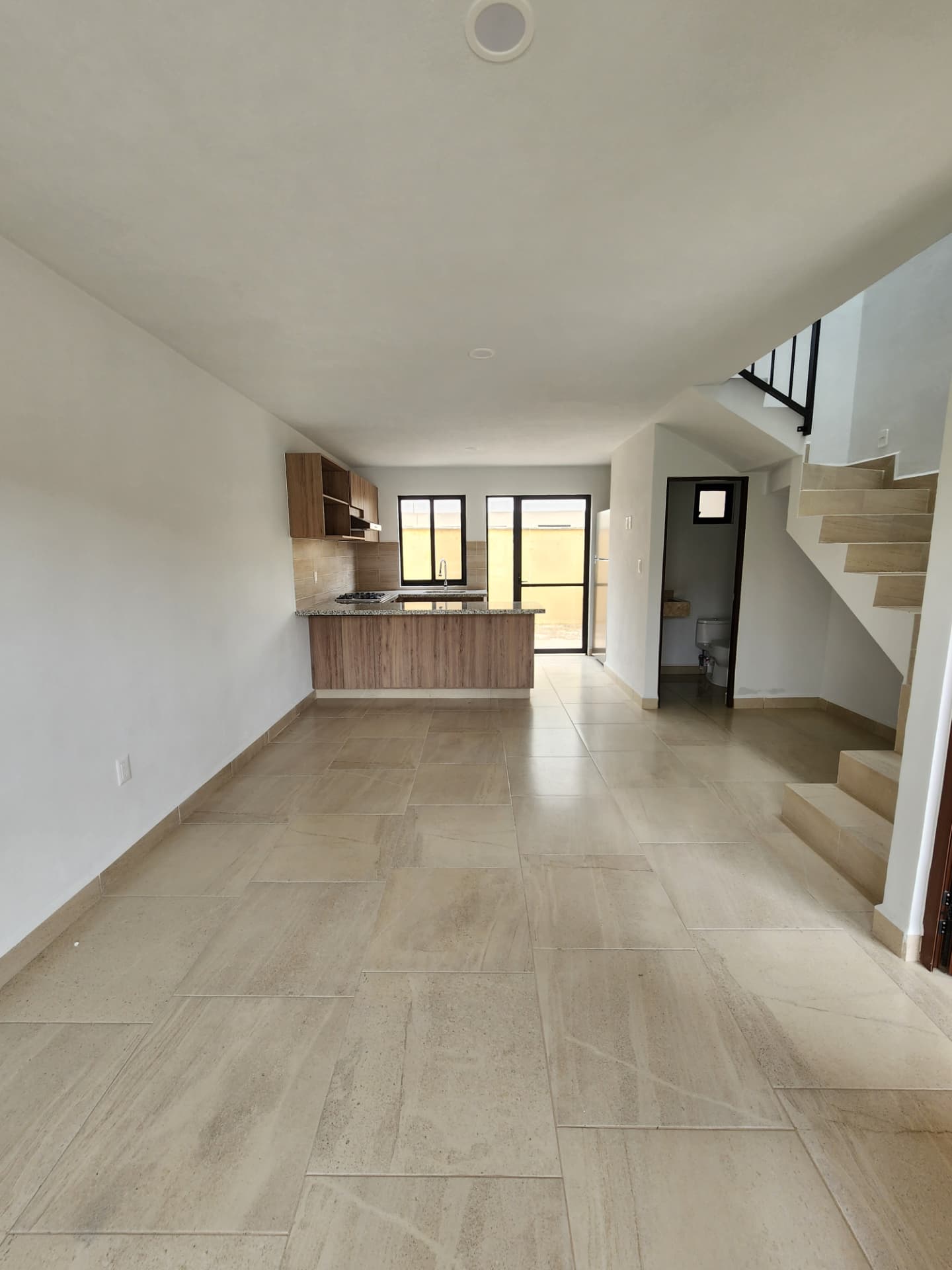 Sala / comedor integrado a la cocina con medio baño y escalera