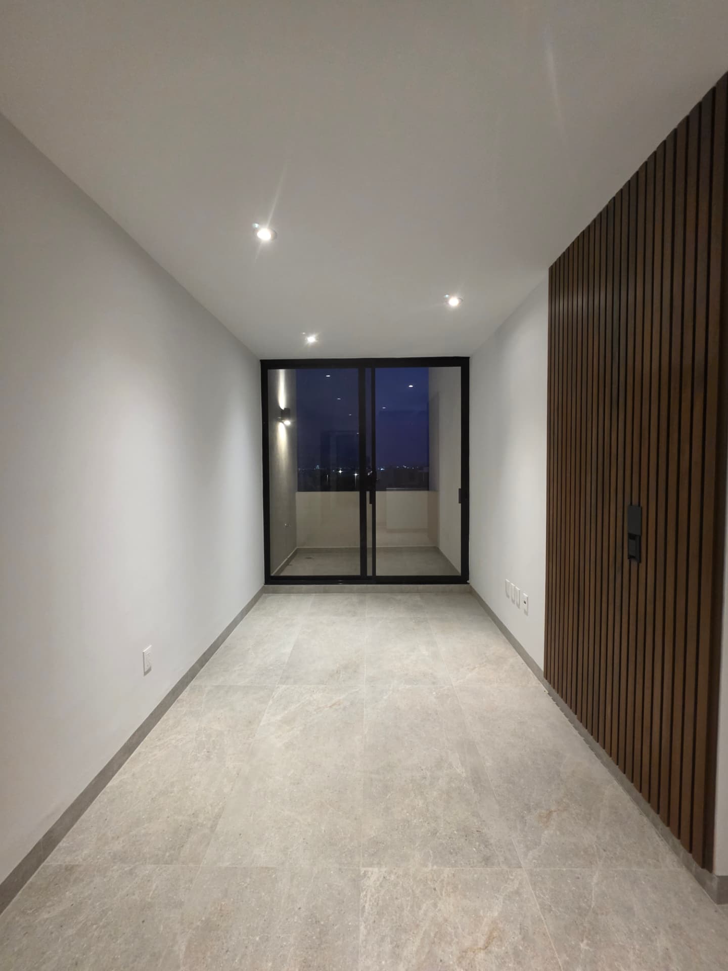 Sala de TV en planta alta con lambrín de madera y salida a balcón