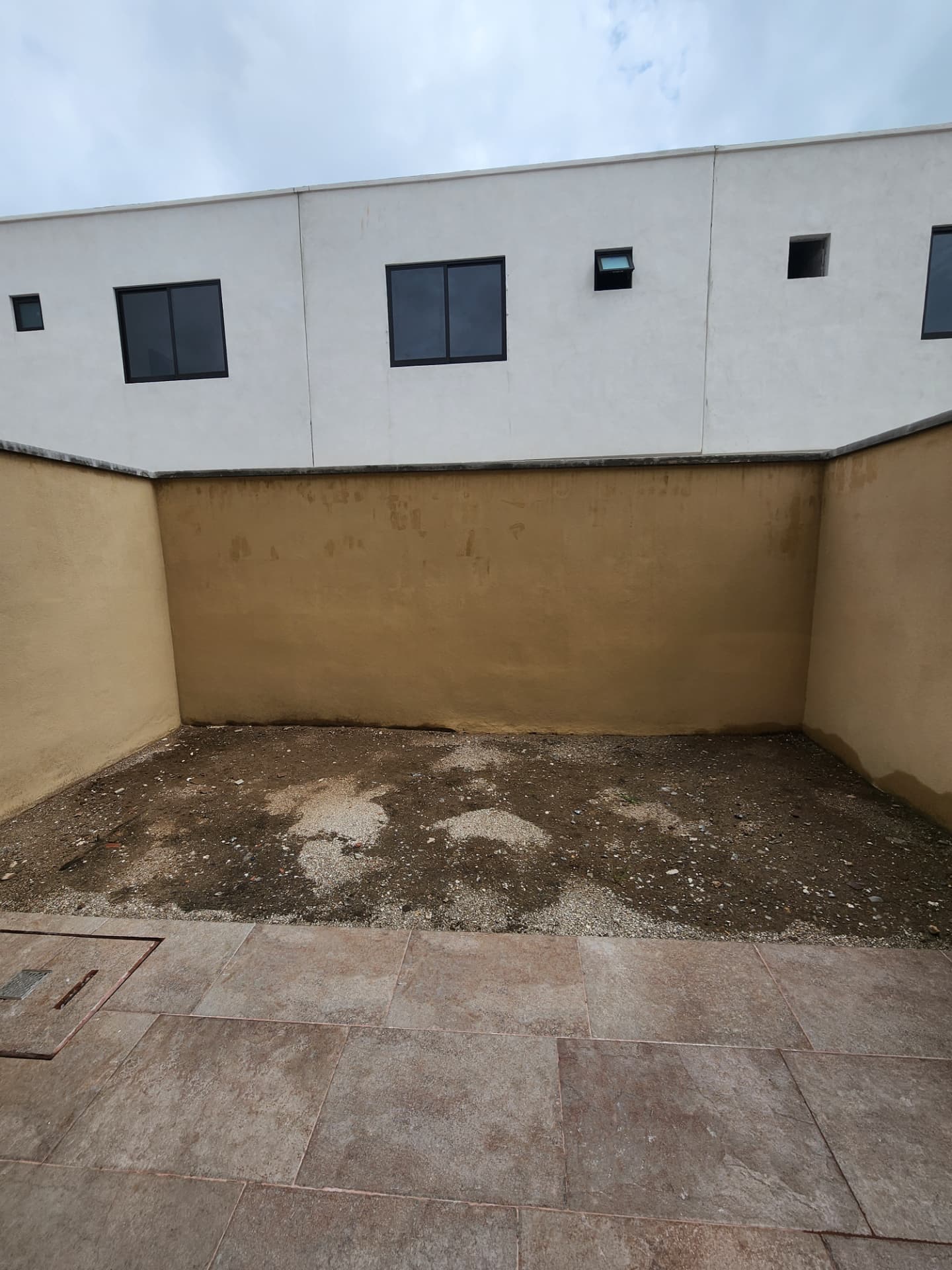 Jardín posterior con piso de cantera y espacio para áreas verdes