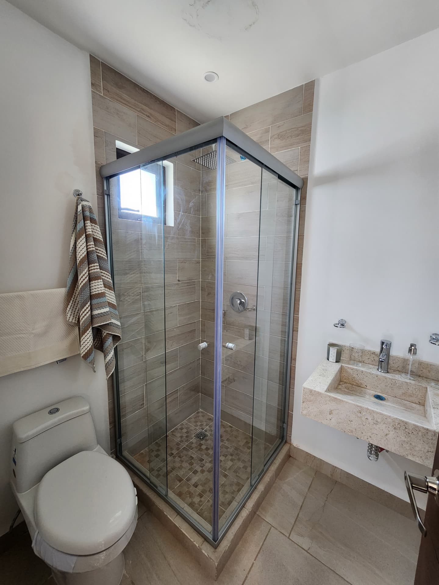 Baño completo con regadera de cristal y lavabo de mármol