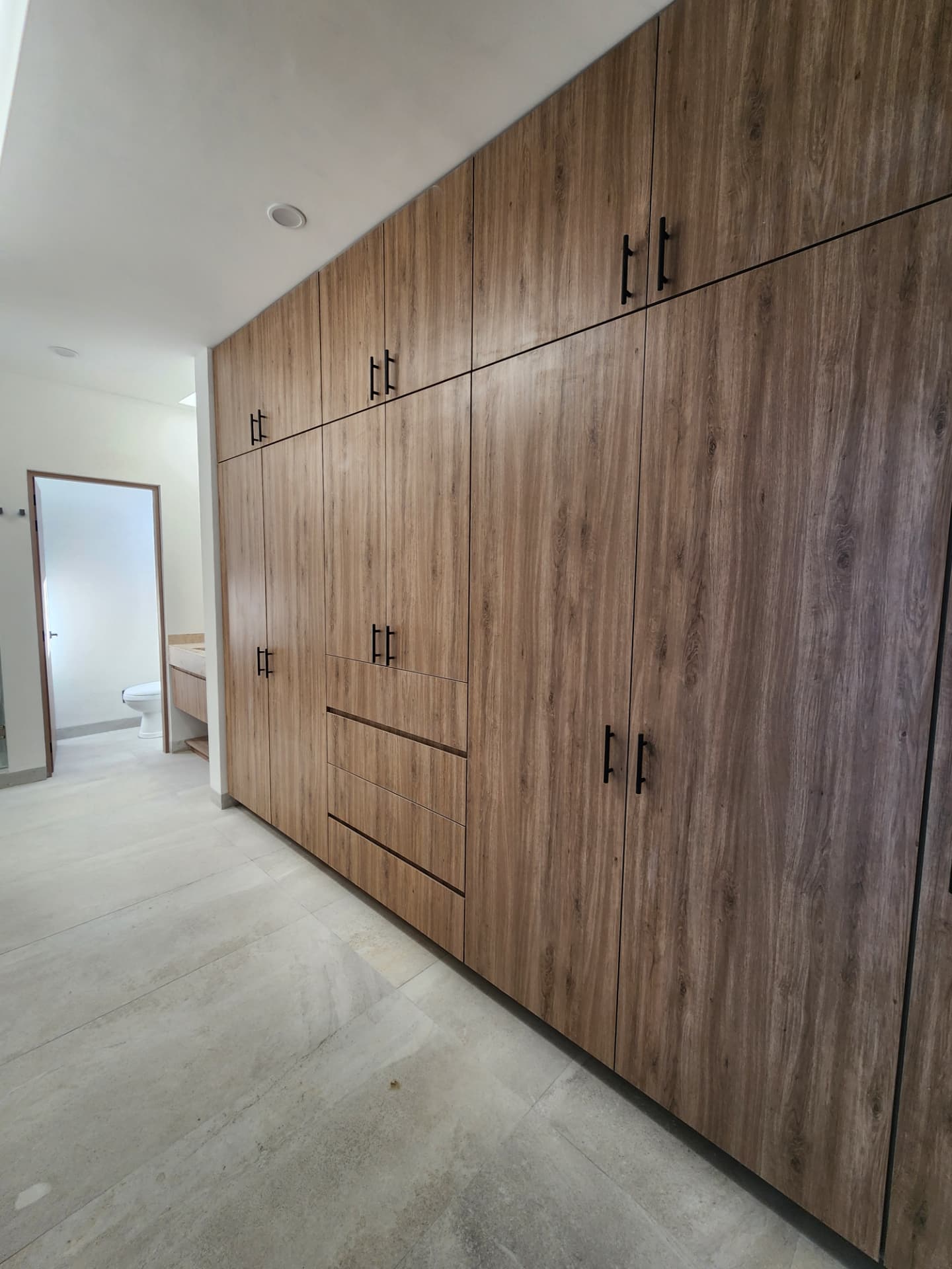 Vestidor amplio con clósets de madera y acceso al baño