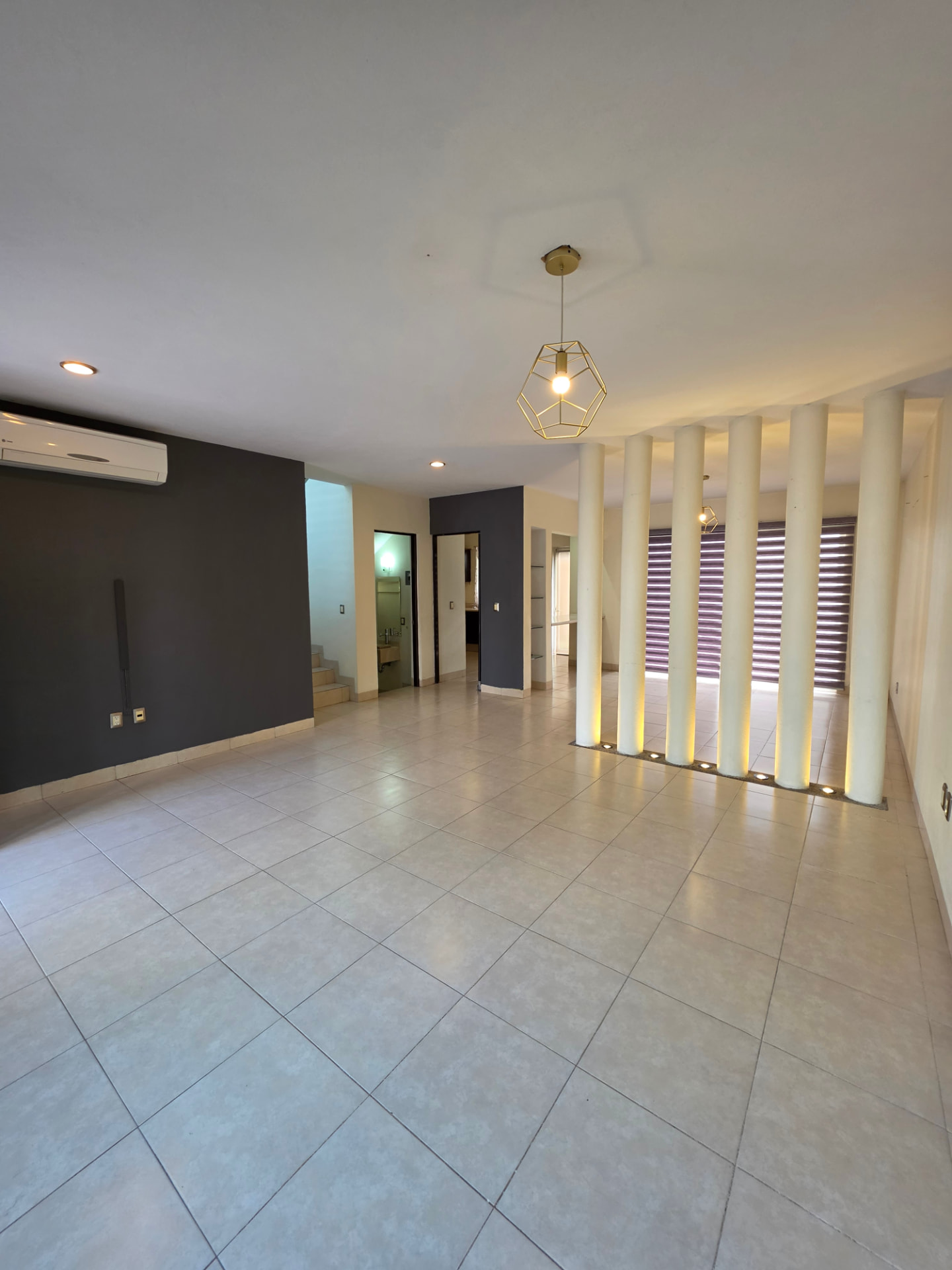 Estancia con minisplit, acceso a medio baño y escalera