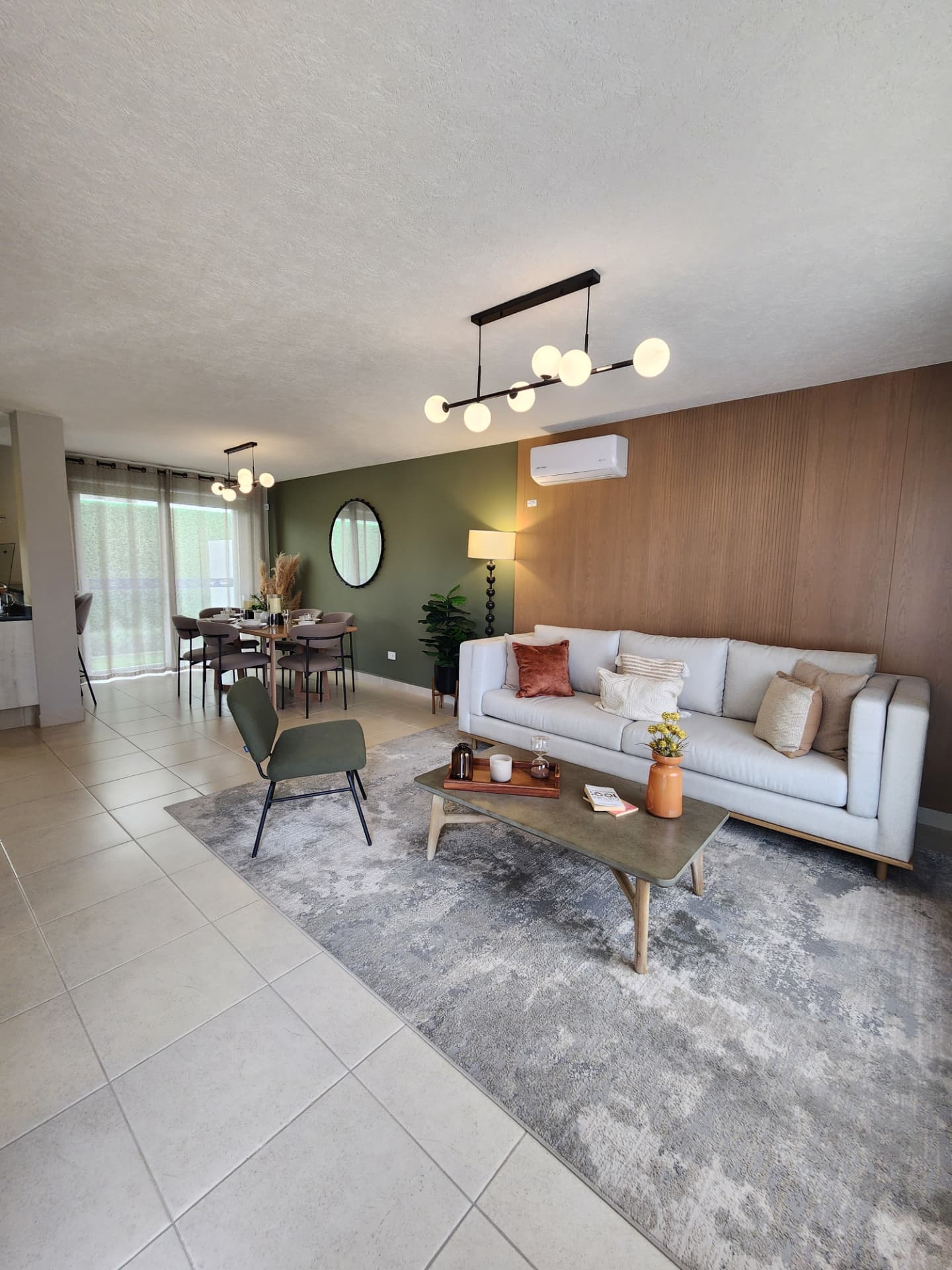 Sala y comedor amueblados con muro de acento verde y lambrín de madera
