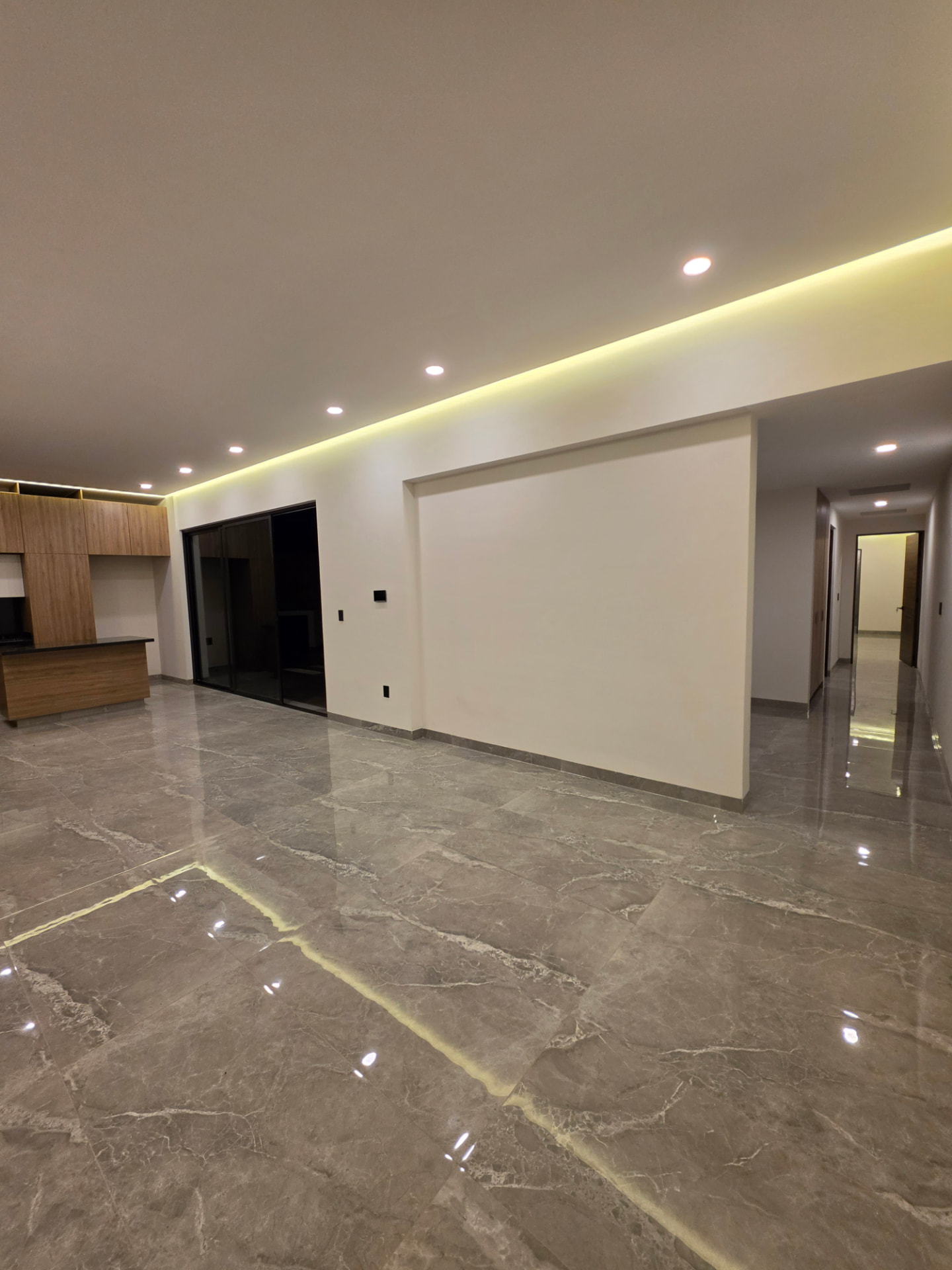 Sala amplia con piso de mármol pulido e iluminación LED indirecta