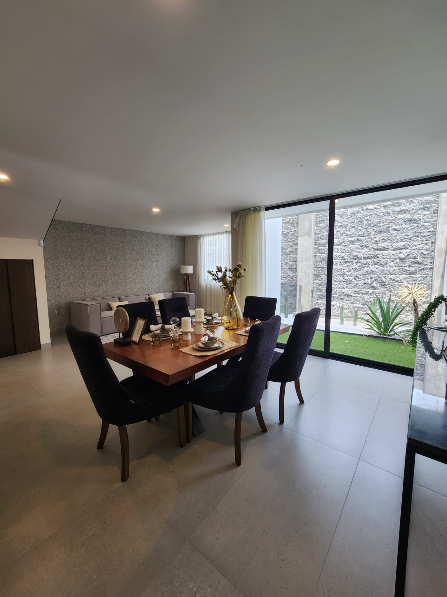 Comedor con ventanal de piso a techo hacia el jardín
