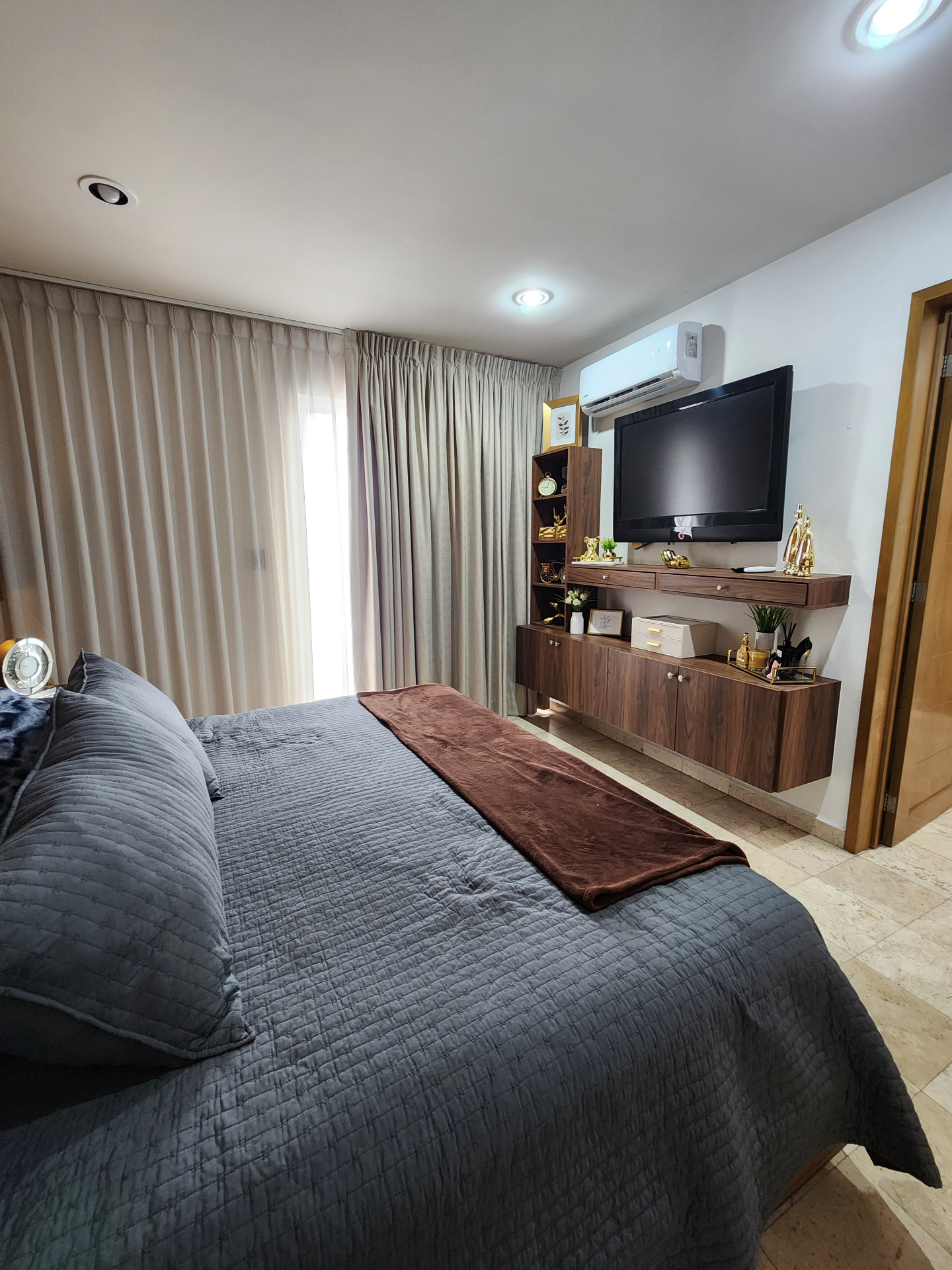 Recámara con mueble de TV, clóset empotrado y ventanal de piso a techo