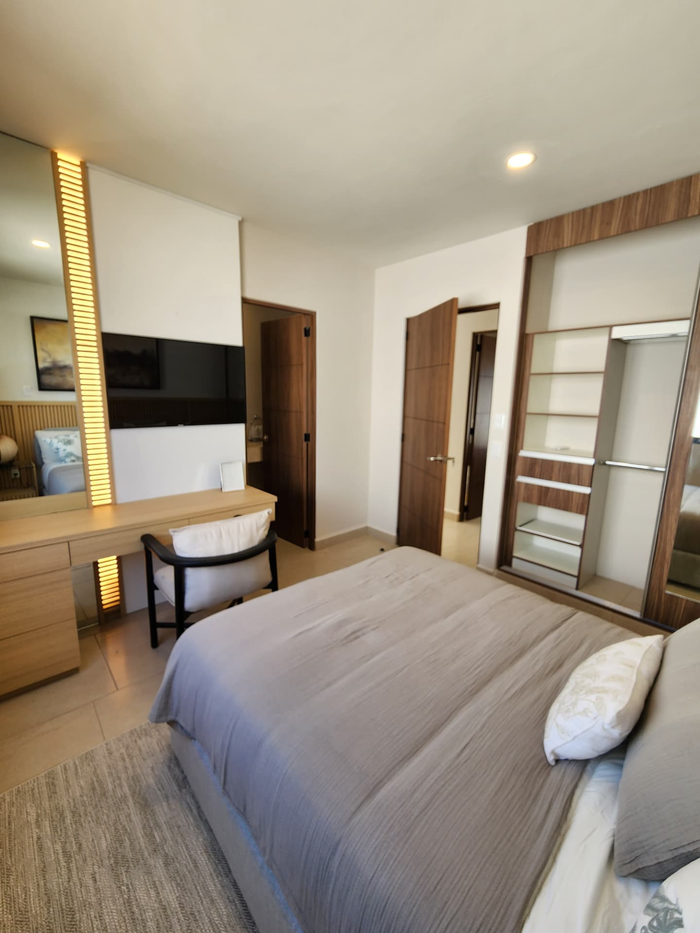 Recámara con tocador, TV y vestidor iluminado