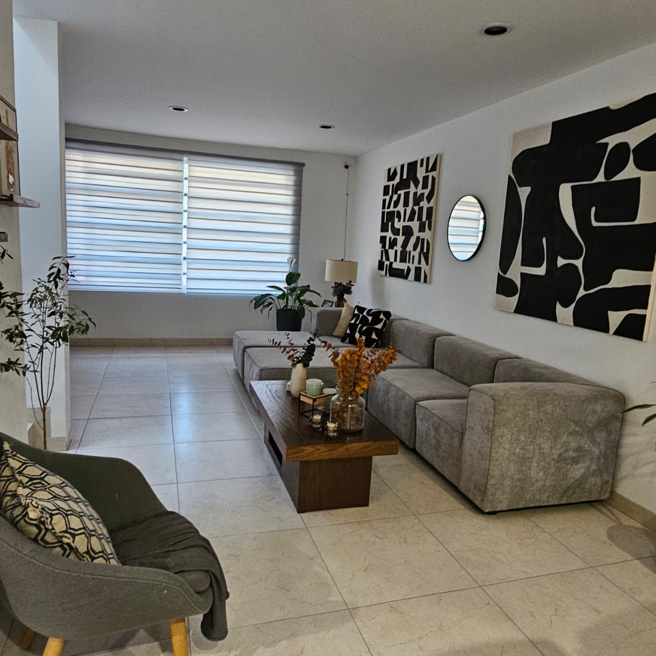 Sala amplia con ventanal, persianas duo y arte contemporáneo