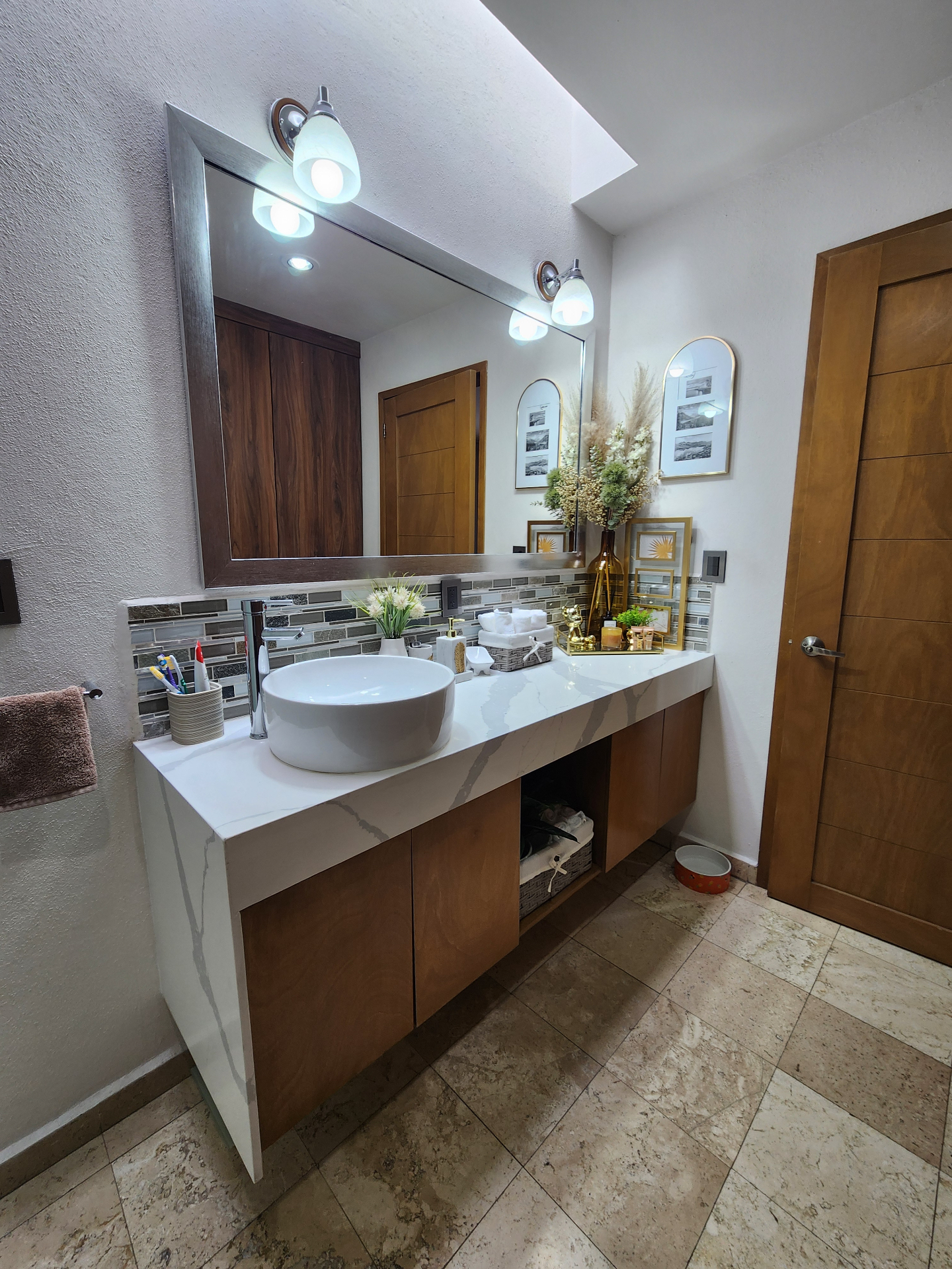 Baño con cubierta tipo mármol, lavabo sobrepuesto y carpintería cálida