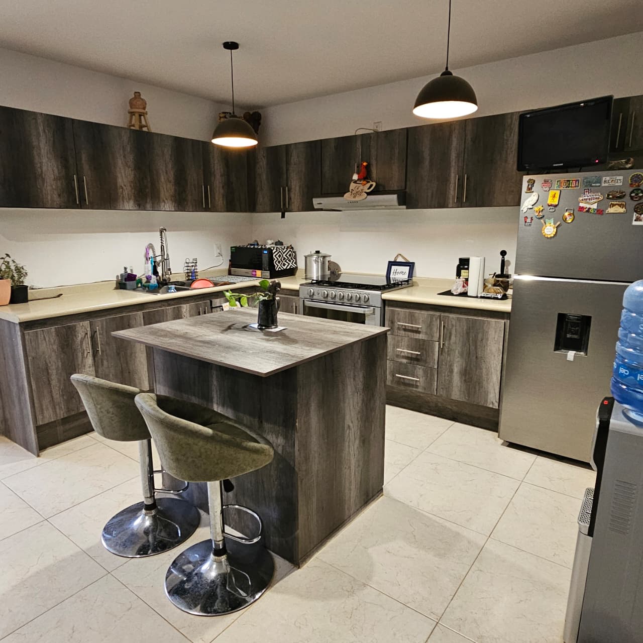 Cocina equipada con isla central, estufa de gas y alacenas en madera