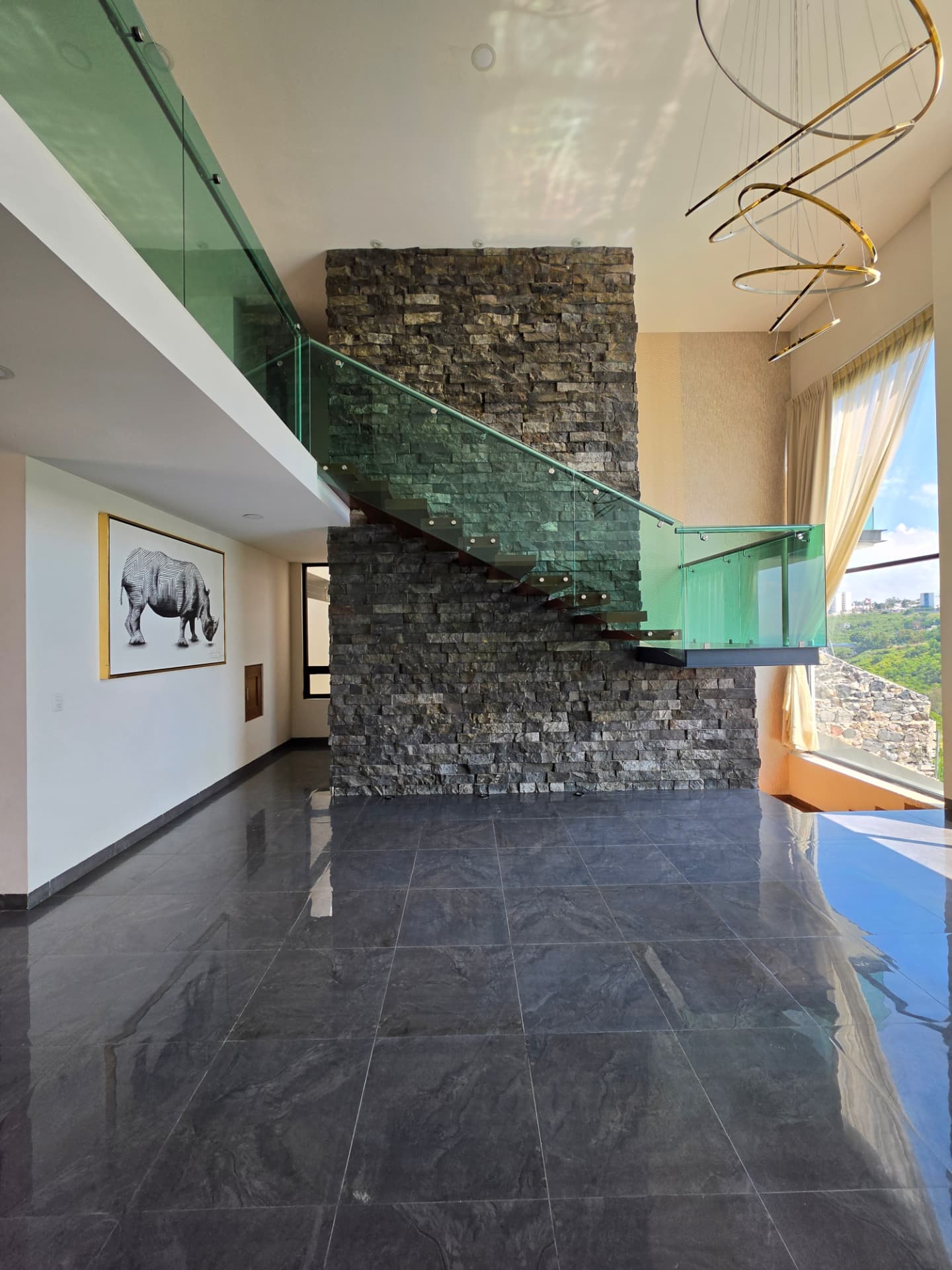 Sala con doble altura y escalera de cristal