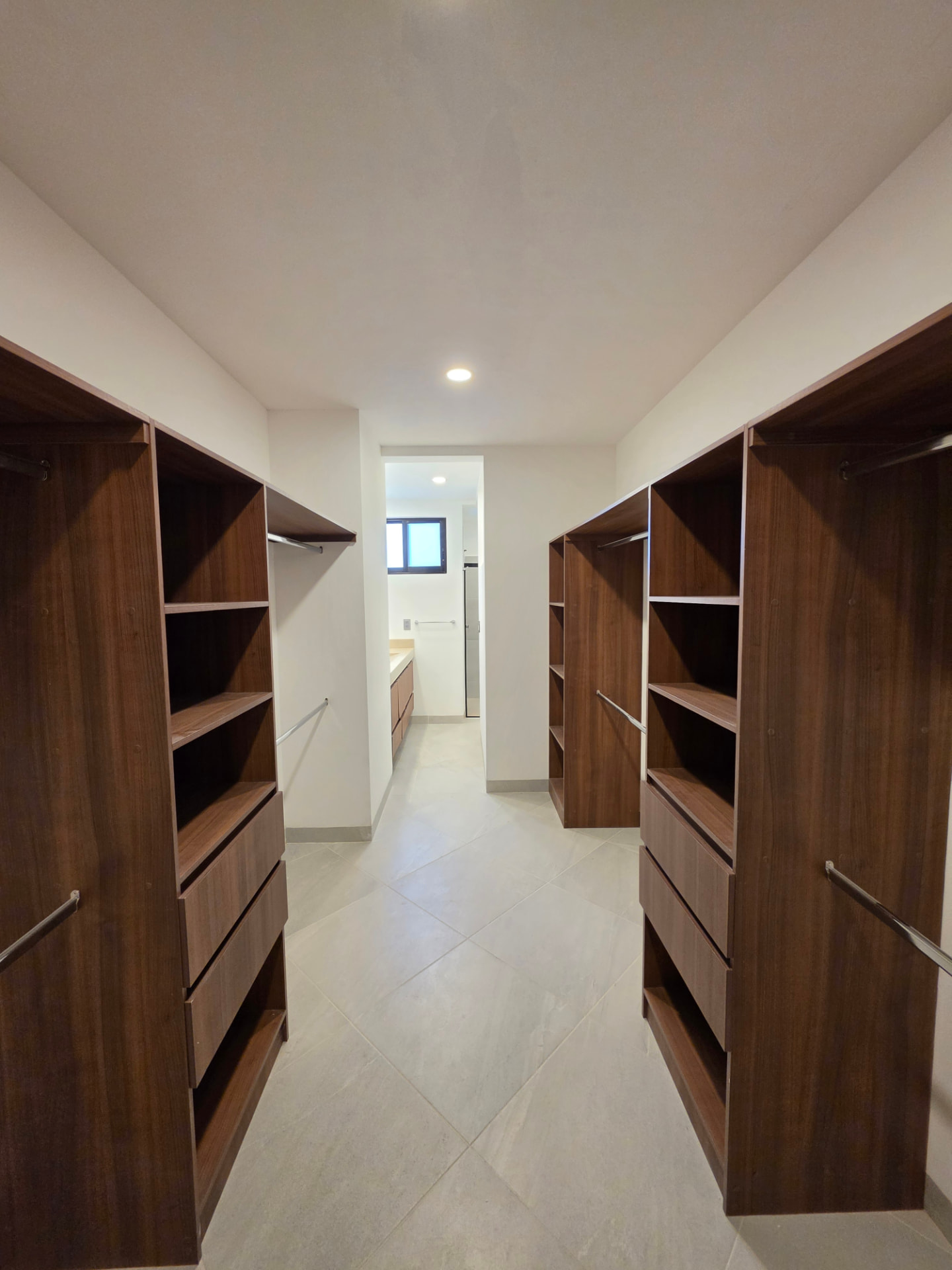 Vestidor amplio con carpintería en madera y acceso al baño