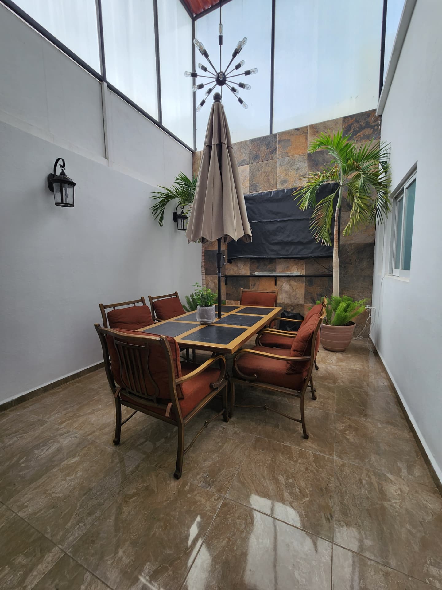Patio con asador, techo traslúcido y comedor exterior