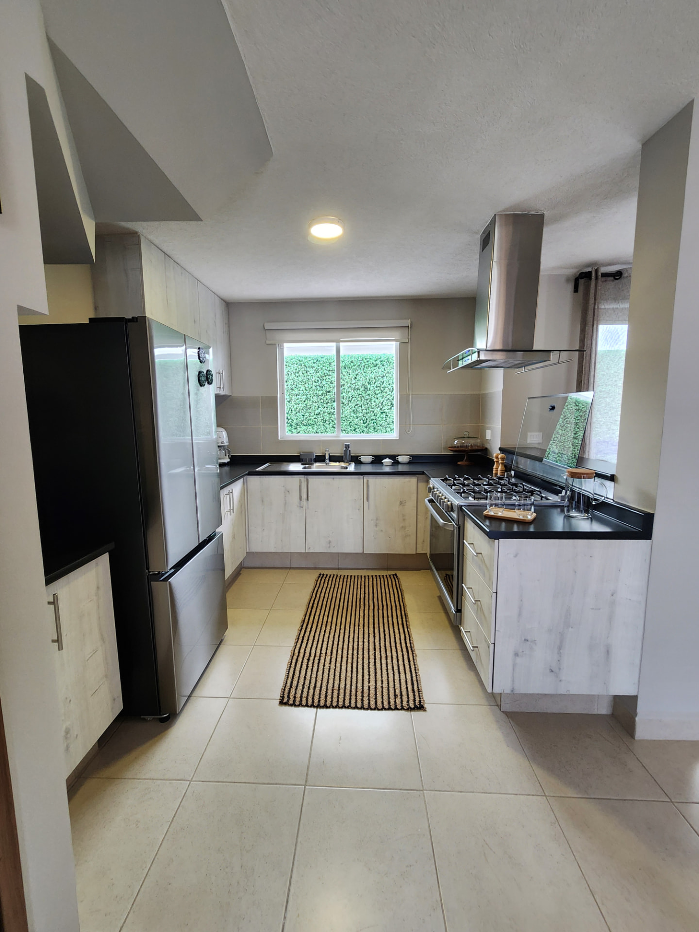 Cocina amueblada con campana, parrilla y vista al jardín