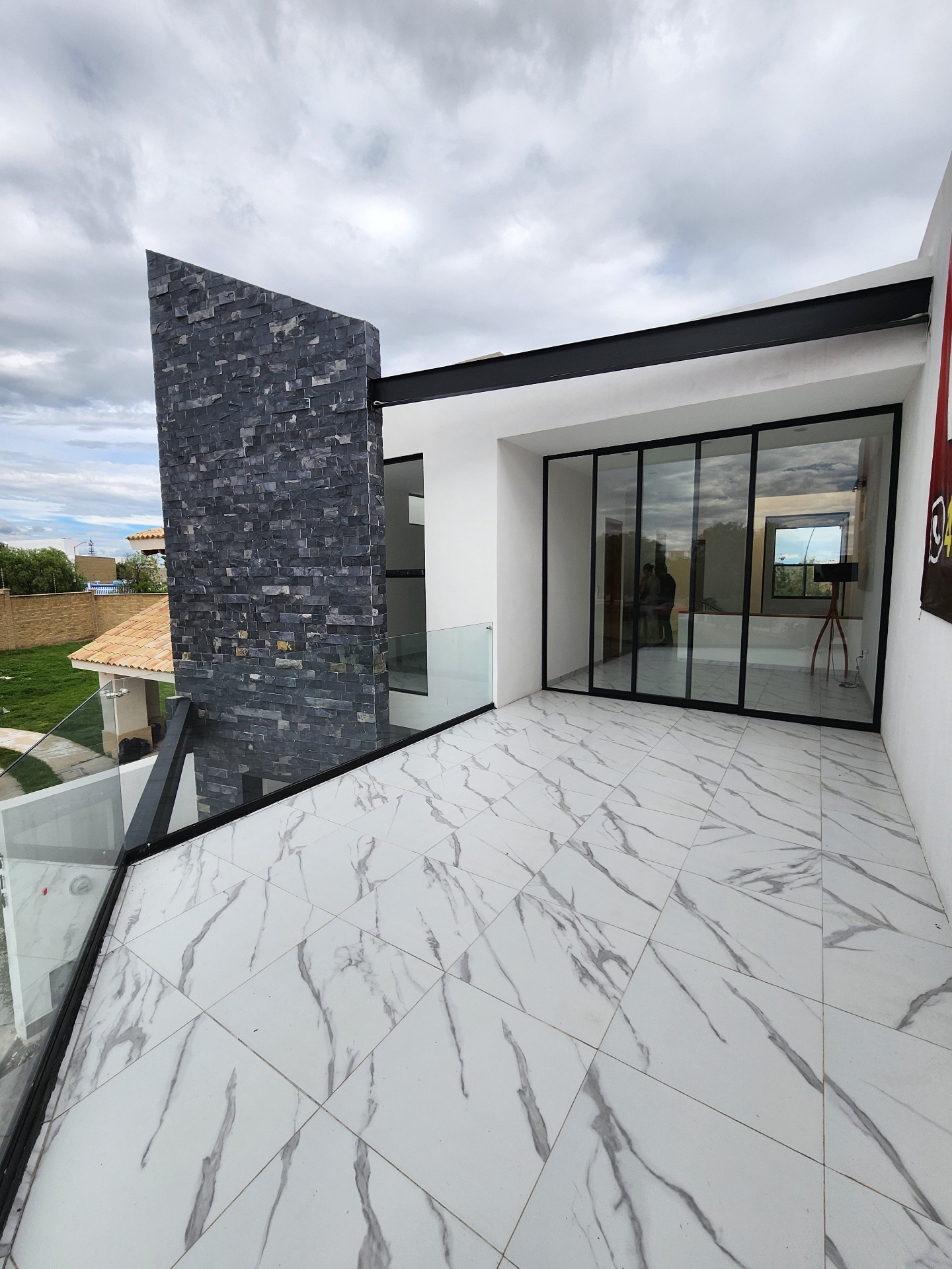 Terraza superior con barandal de cristal y vista abierta hacia el entorno