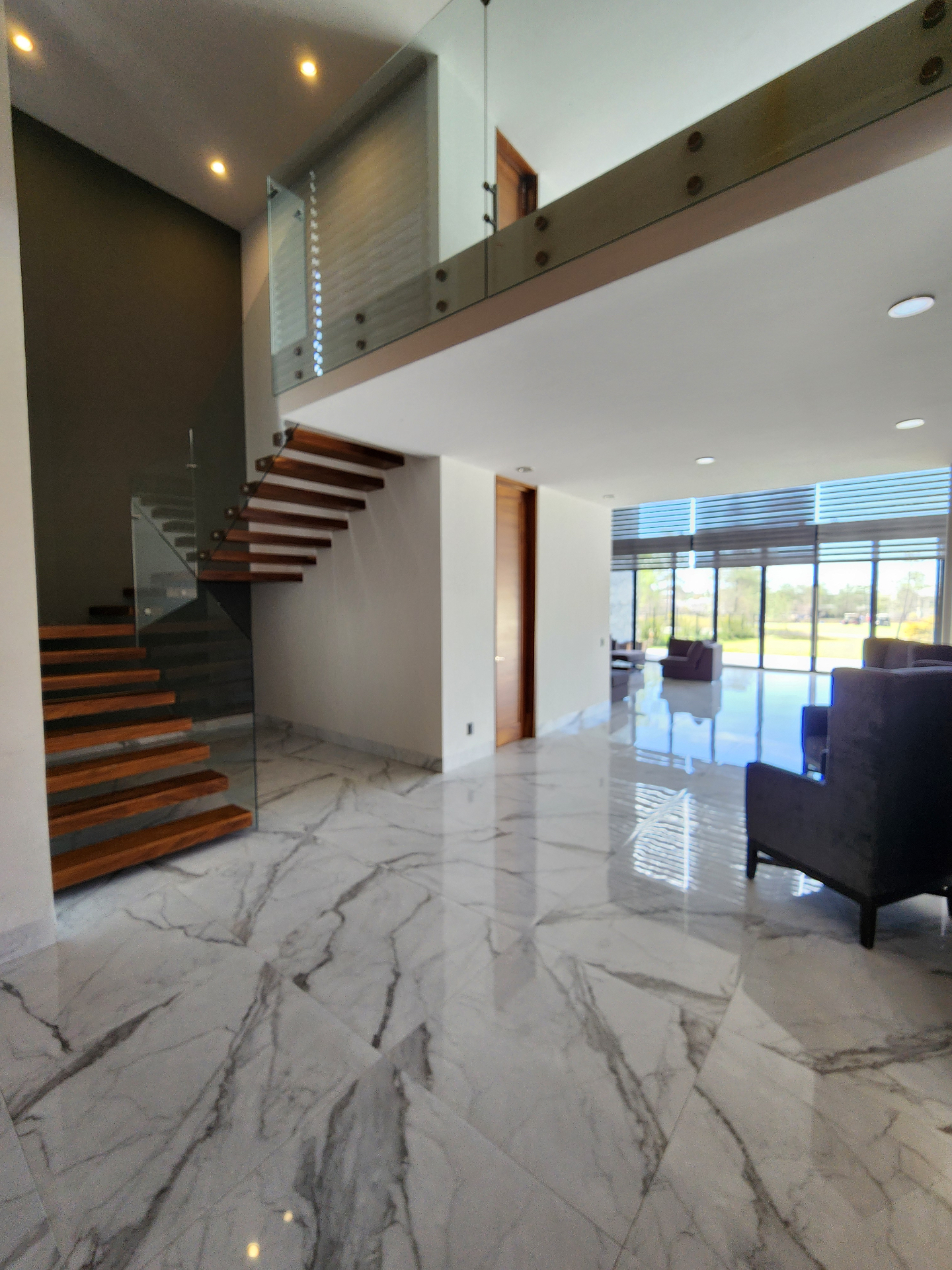 Vestíbulo con escaleras flotantes y doble altura