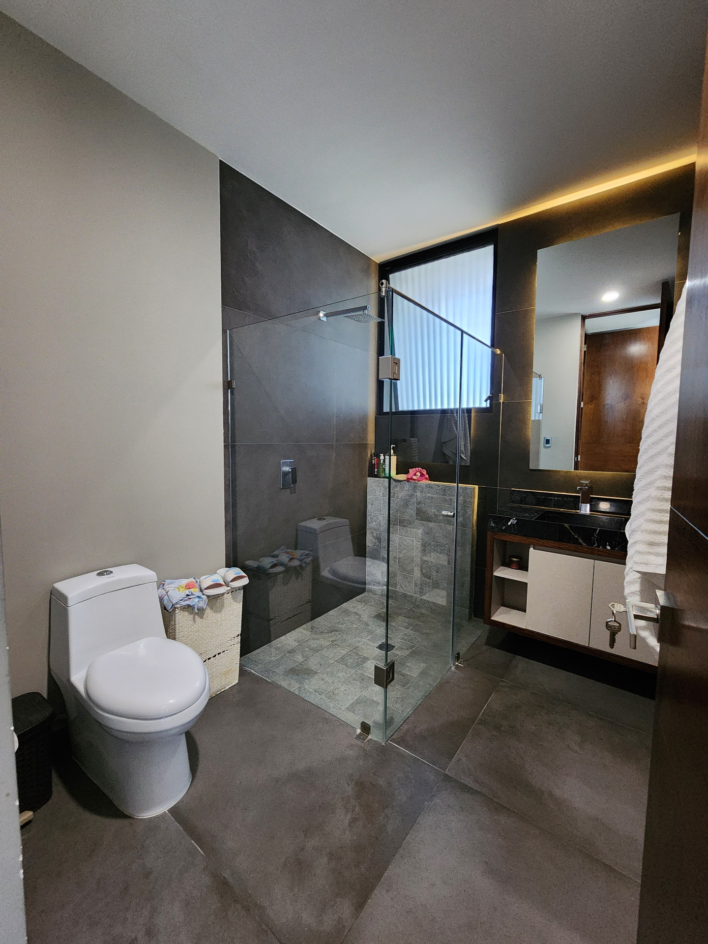 Baño con regadera de cristal, cancelería negra y cubierta de mármol