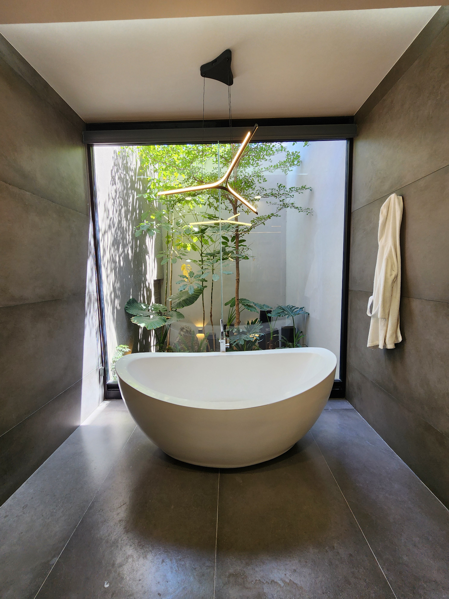 Baño principal con tina exenta y jardín interior con doble altura