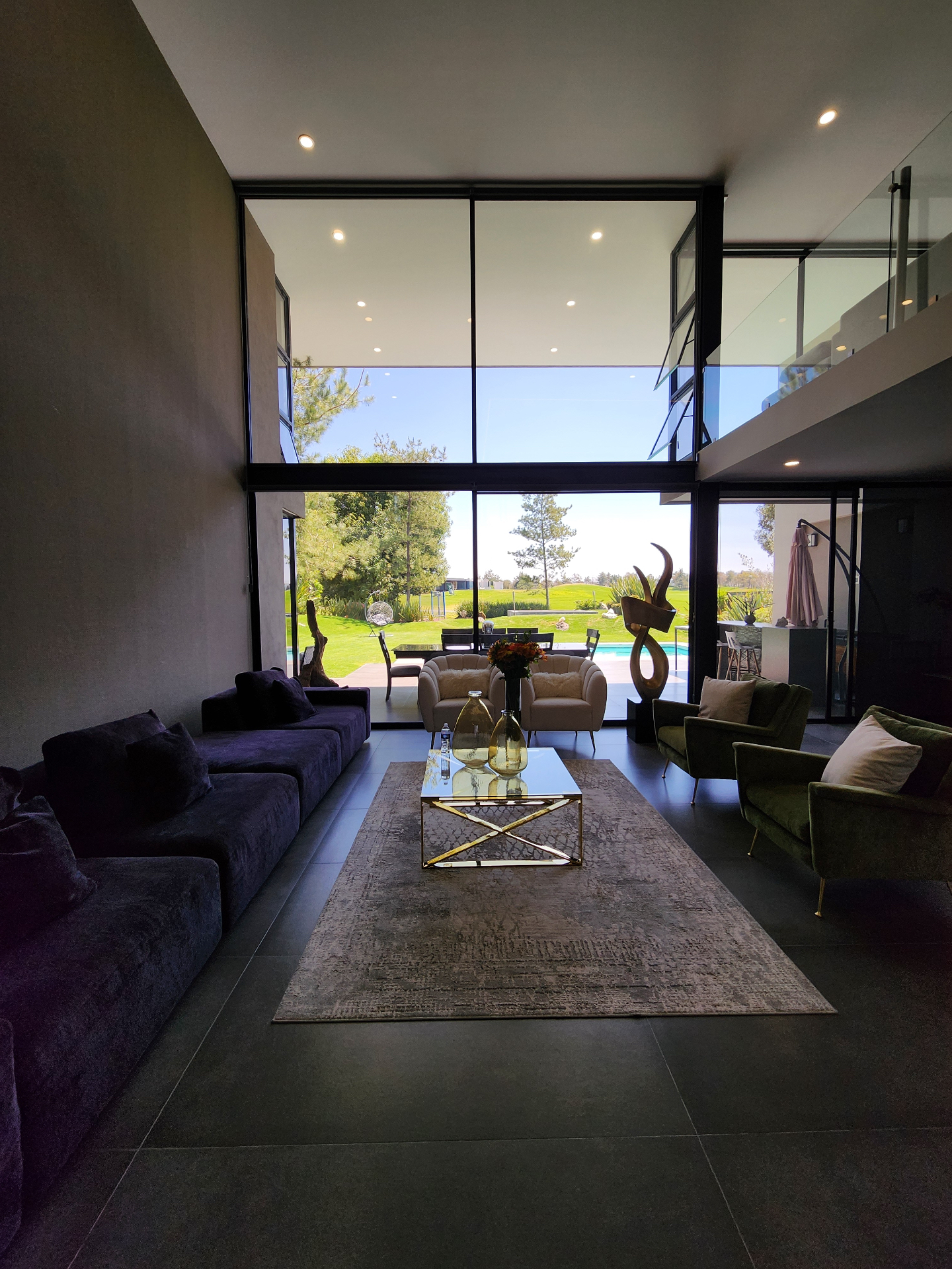 Sala con doble altura y ventanal al campo de golf y alberca