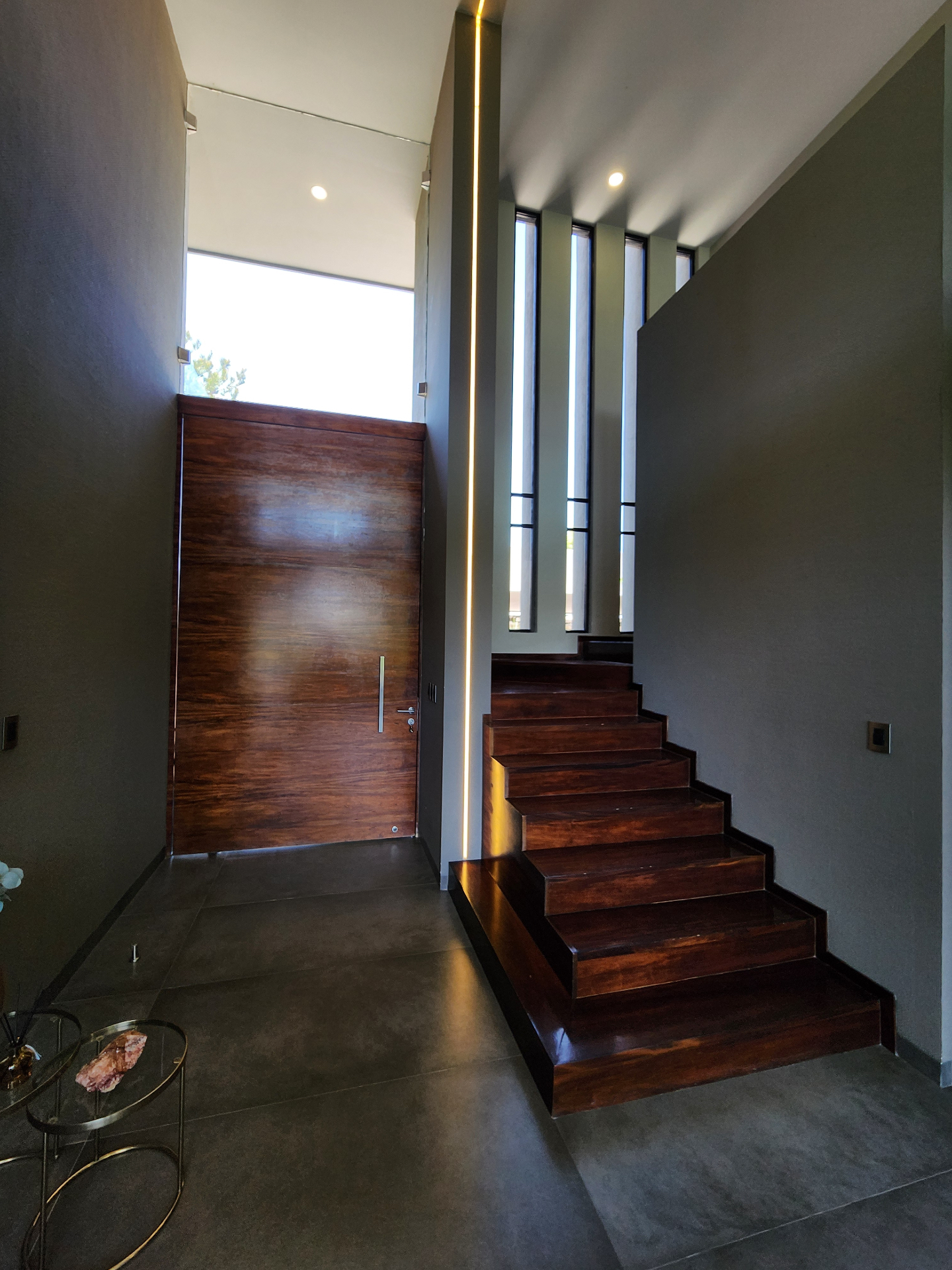 Vestíbulo de acceso con puerta monumental y escalera en madera
