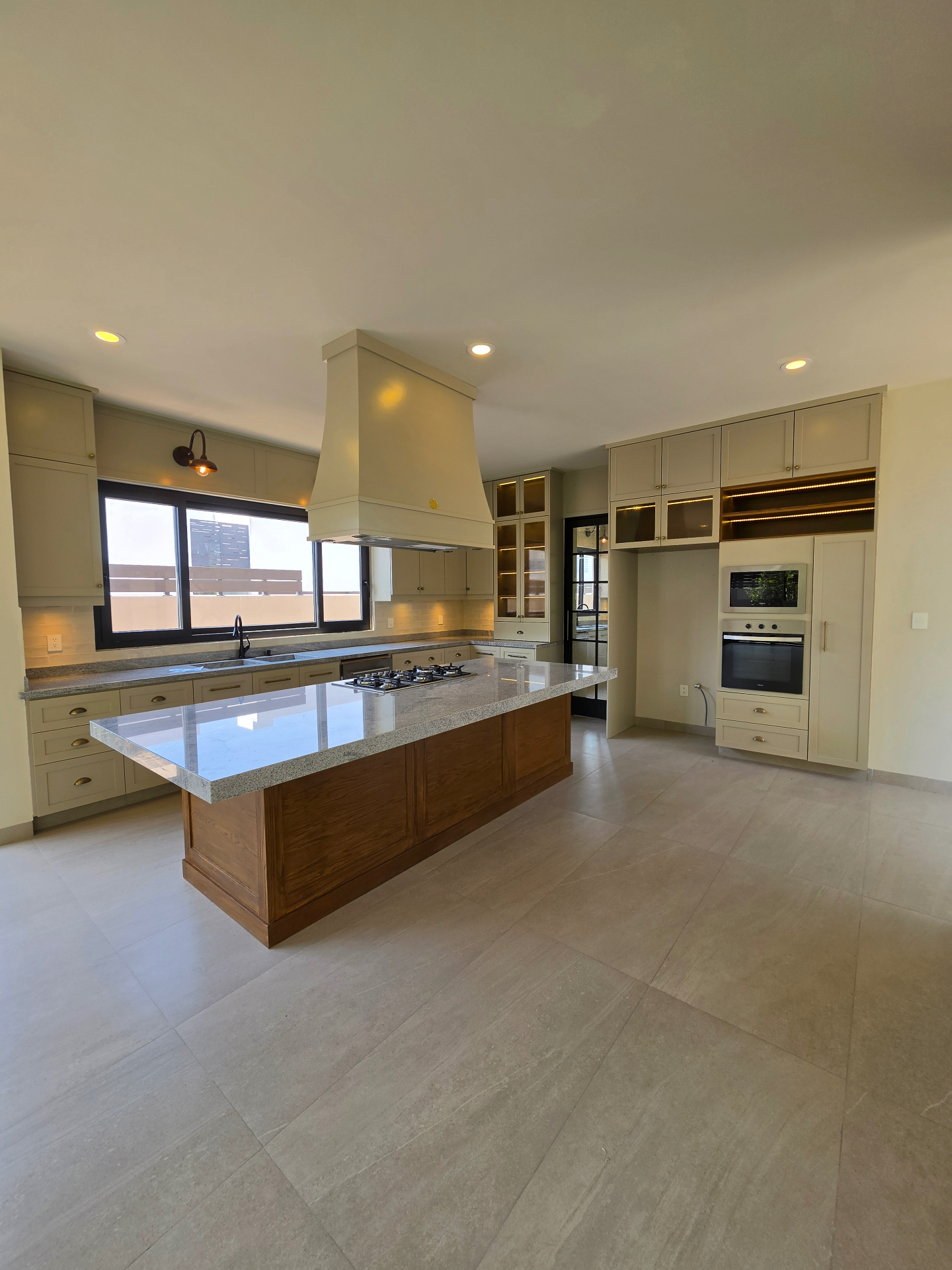 Cocina amplia con isla central, alacena de cristal y horno empotrado