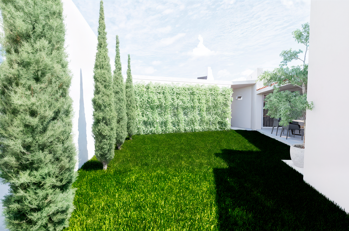 Jardín lateral con pasto natural, cipreses y muro verde hacia la terraza